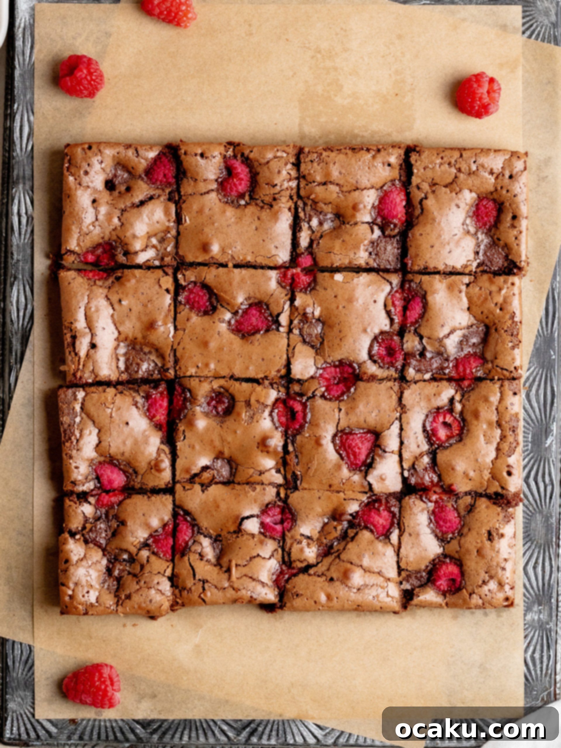A single square of raspberry brownie on a light plate, with a fork, ready to be eaten.