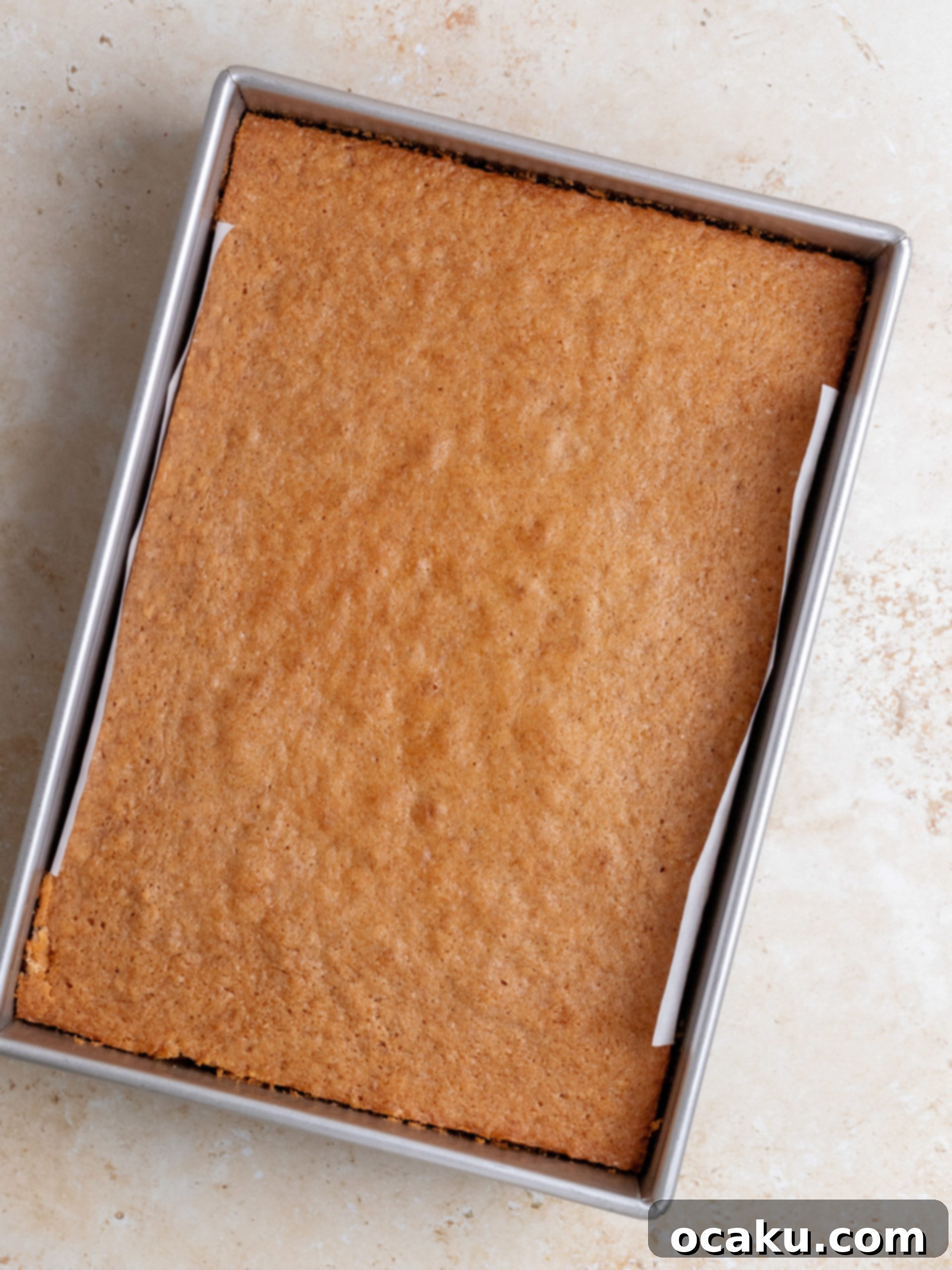 Applying strawberry cream cheese frosting to a cooled sheet cake.