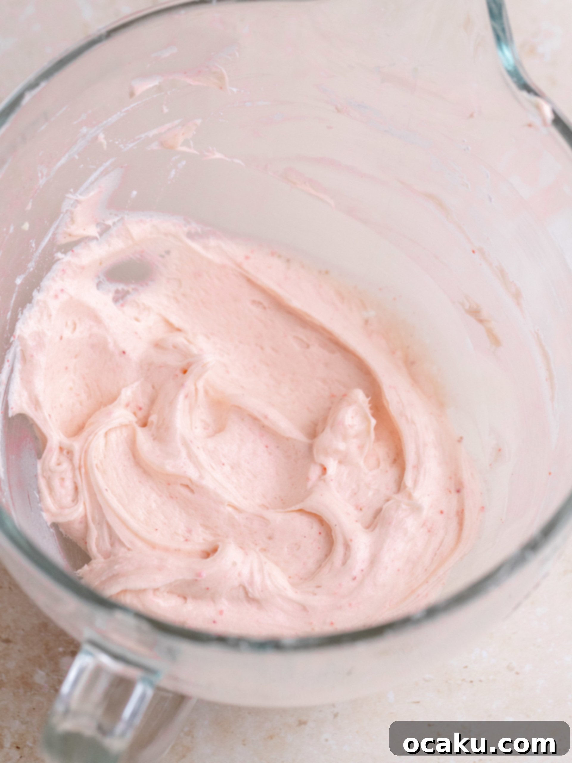 Spreading frosting evenly over the sheet cake with an offset spatula.