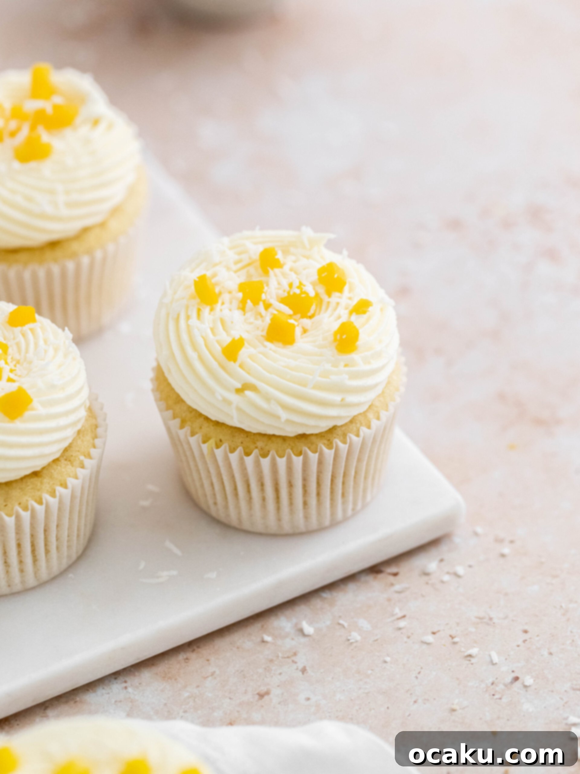 Mango Bliss Cupcakes 2 Soft coconut cupcake, filled with a sweet mango curd and topped with a luxurious coconut and vanilla buttercream, ready to be enjoyed.