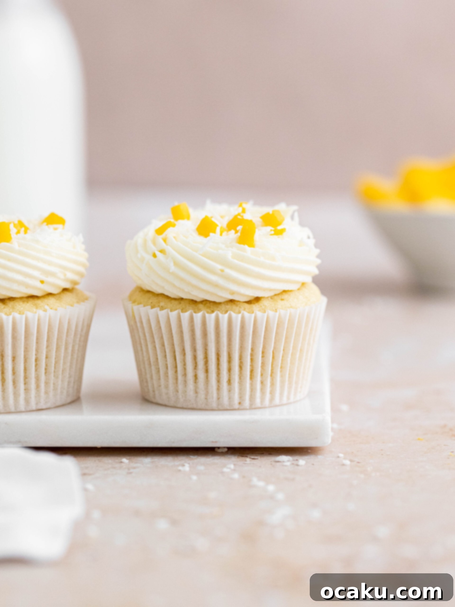 Mango Bliss Cupcakes 6 A perfectly baked coconut cupcake, beautifully filled with vibrant mango curd and generously topped with a creamy coconut buttercream, ready to be devoured.