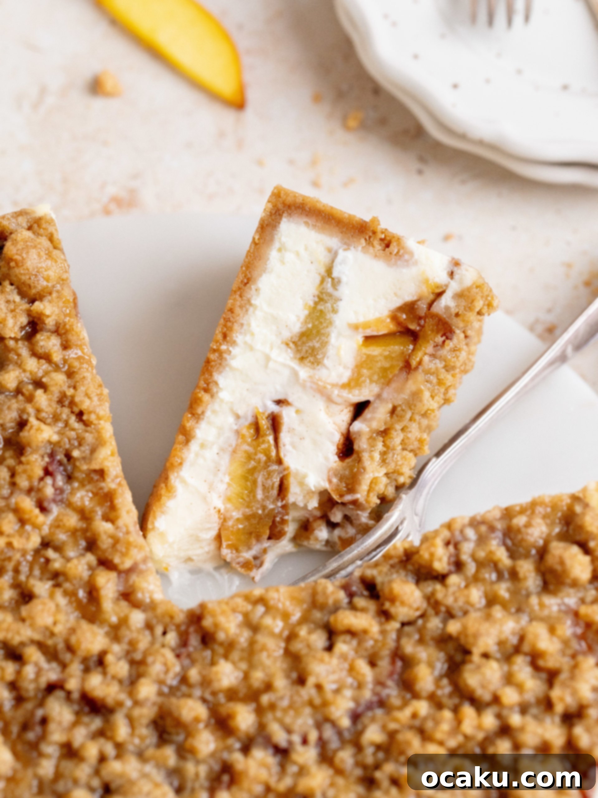A slice of peach crumble cheesecake on a white plate, ready to be enjoyed.