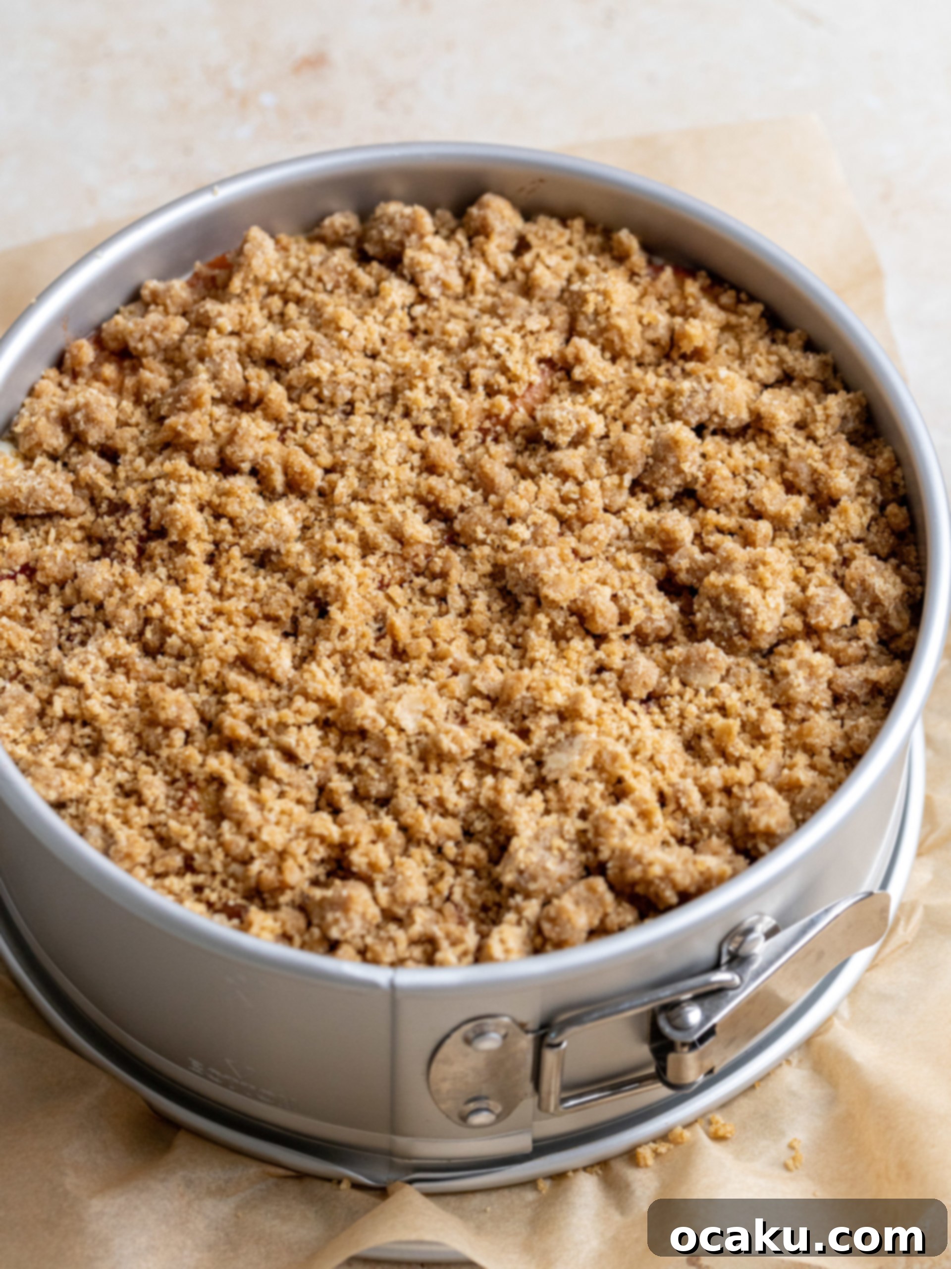 Pouring cheesecake batter into the crust, with peaches layered inside.