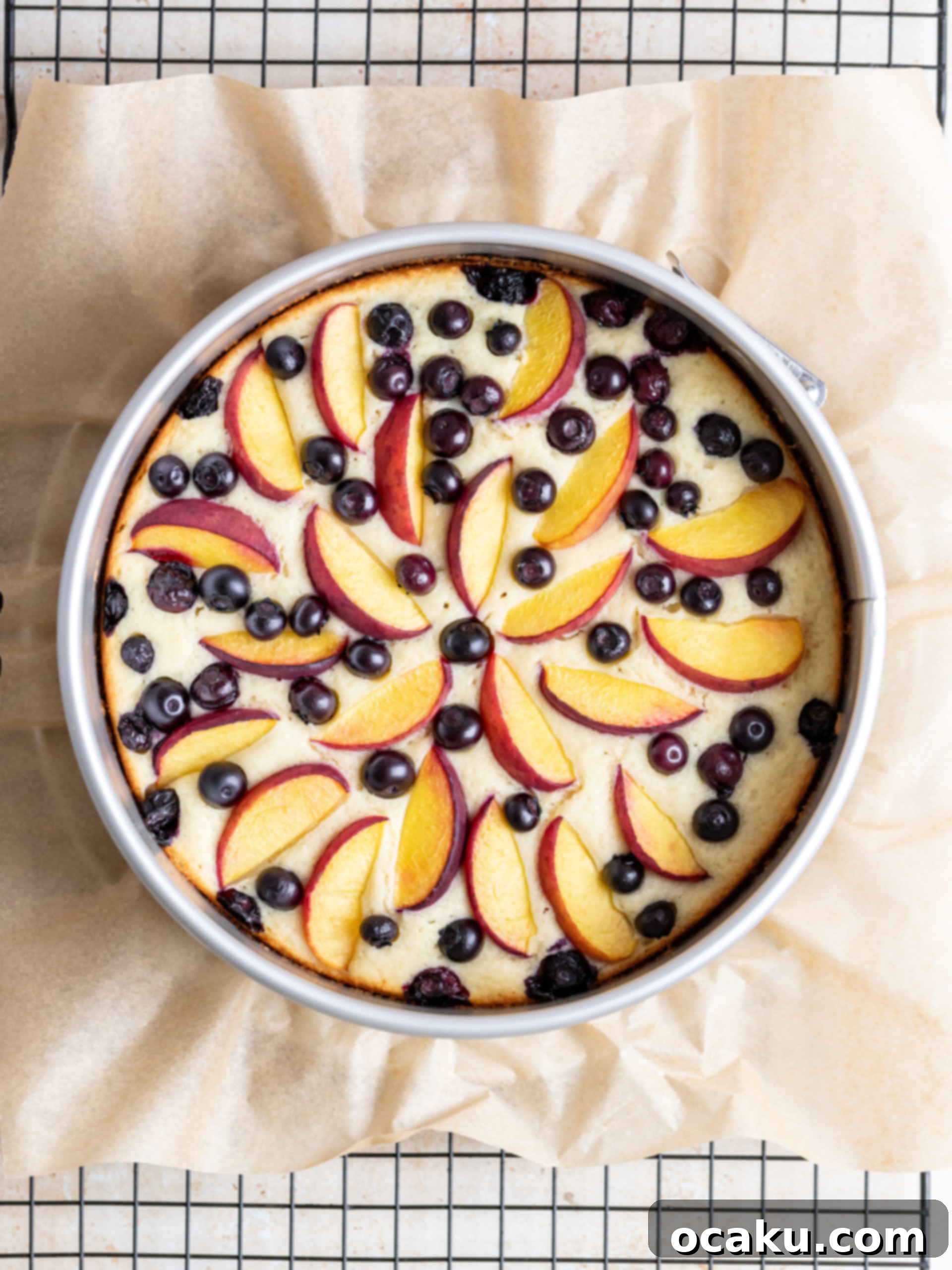 Fresh peach slices being placed on cake batter in a pan.