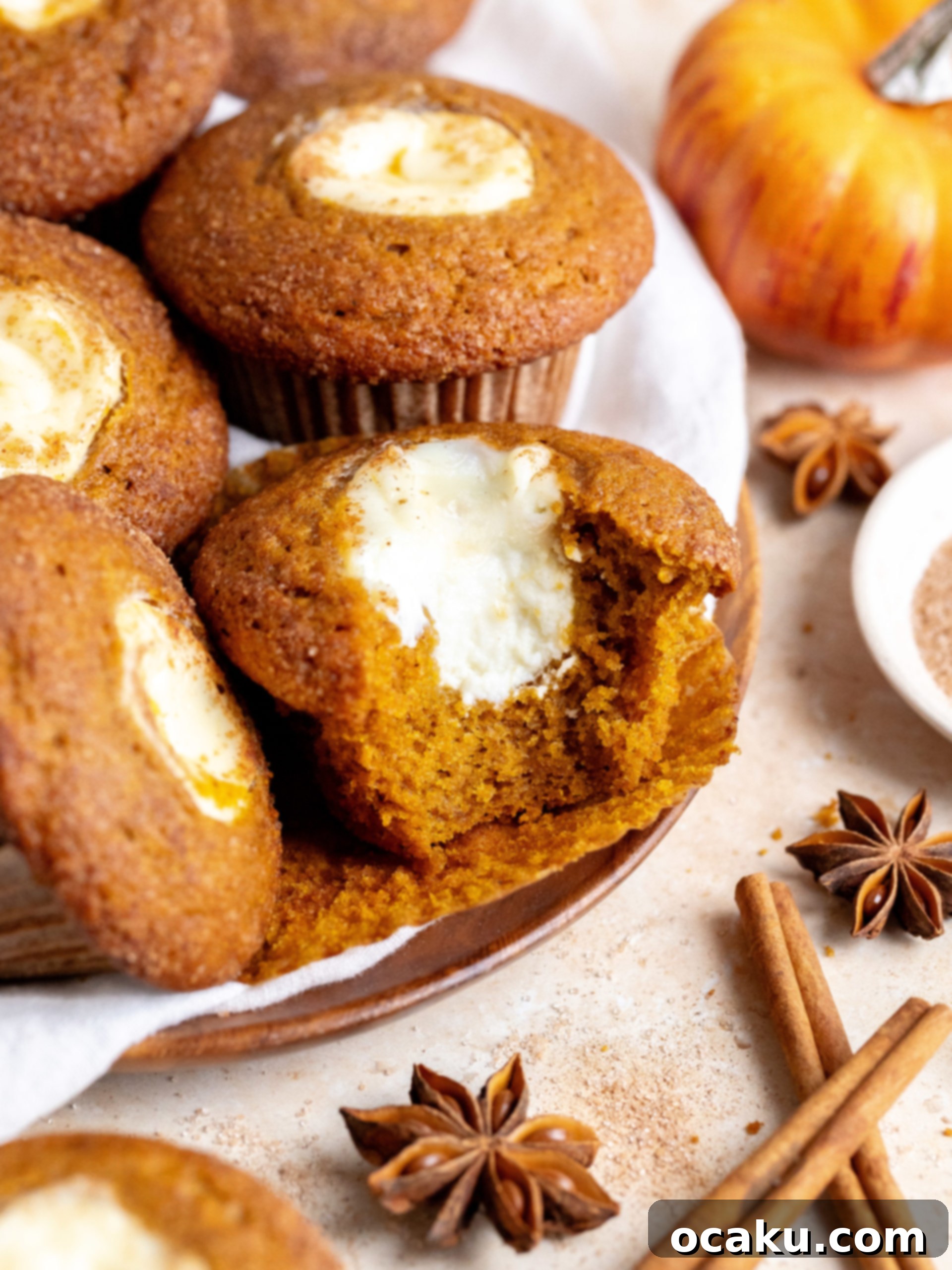 Stacked pumpkin cream cheese muffins on a cooling rack.