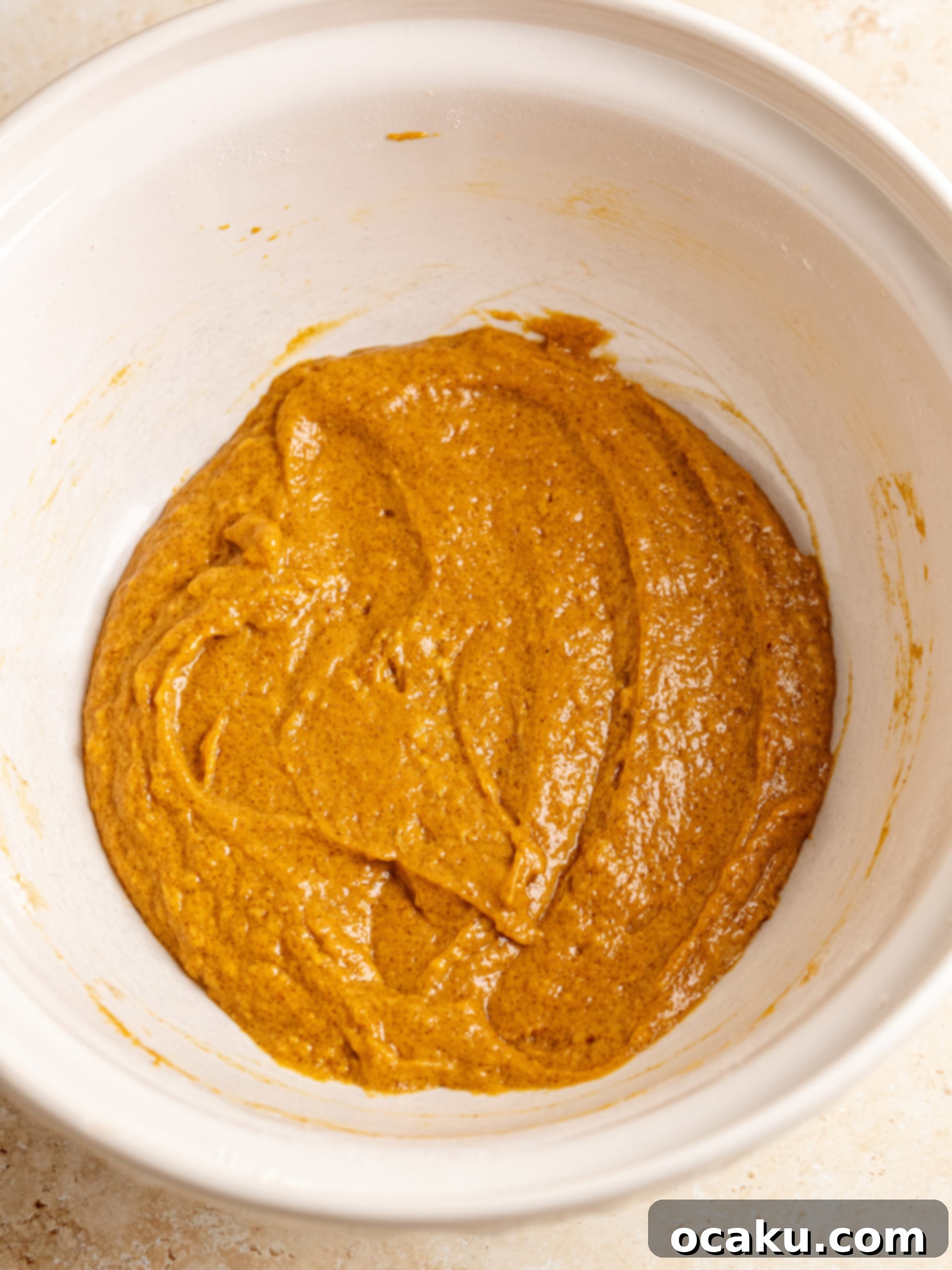 Muffin batter resting in a bowl covered with plastic wrap.