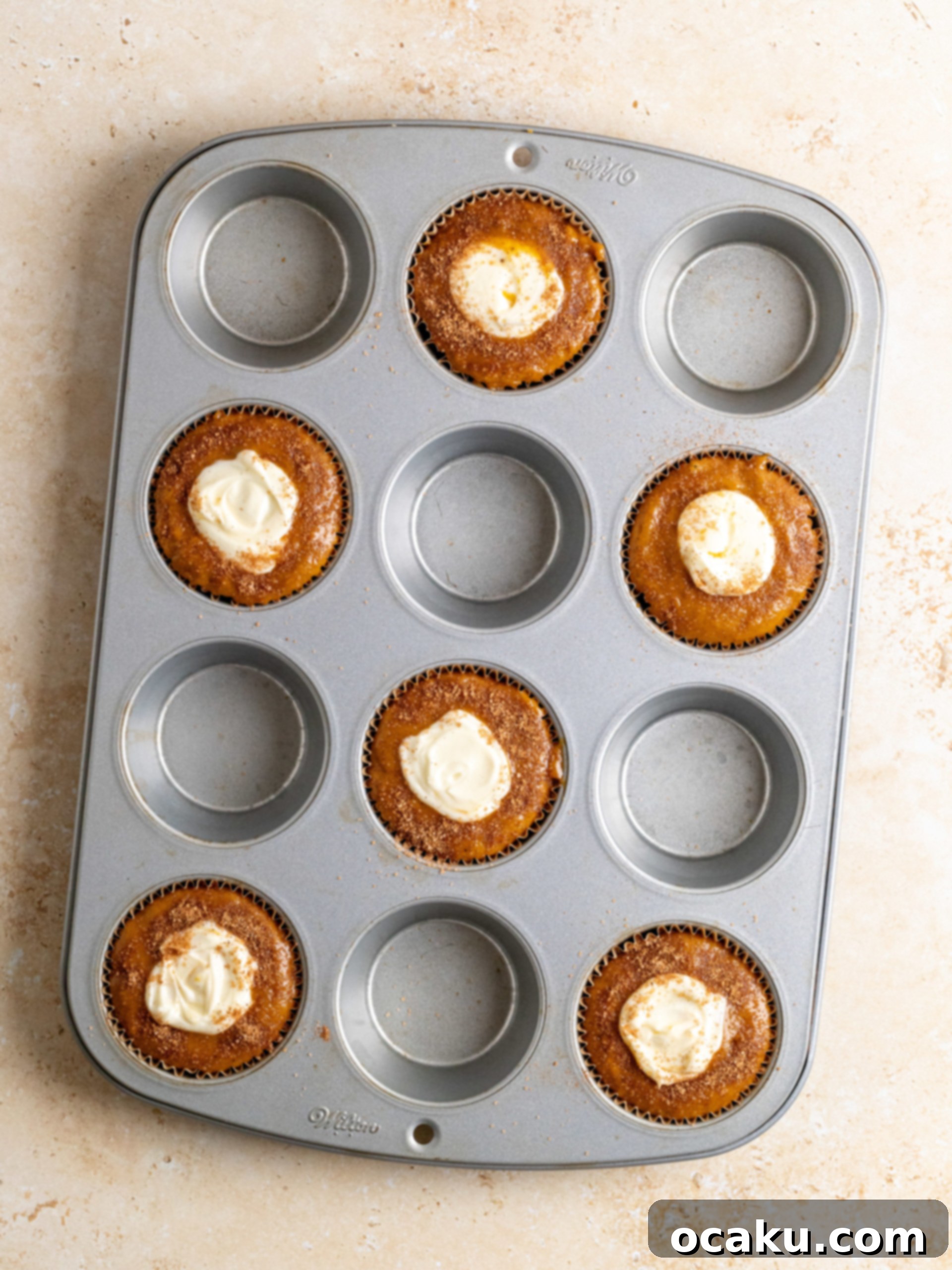 Piping cream cheese filling into pumpkin muffin batter.