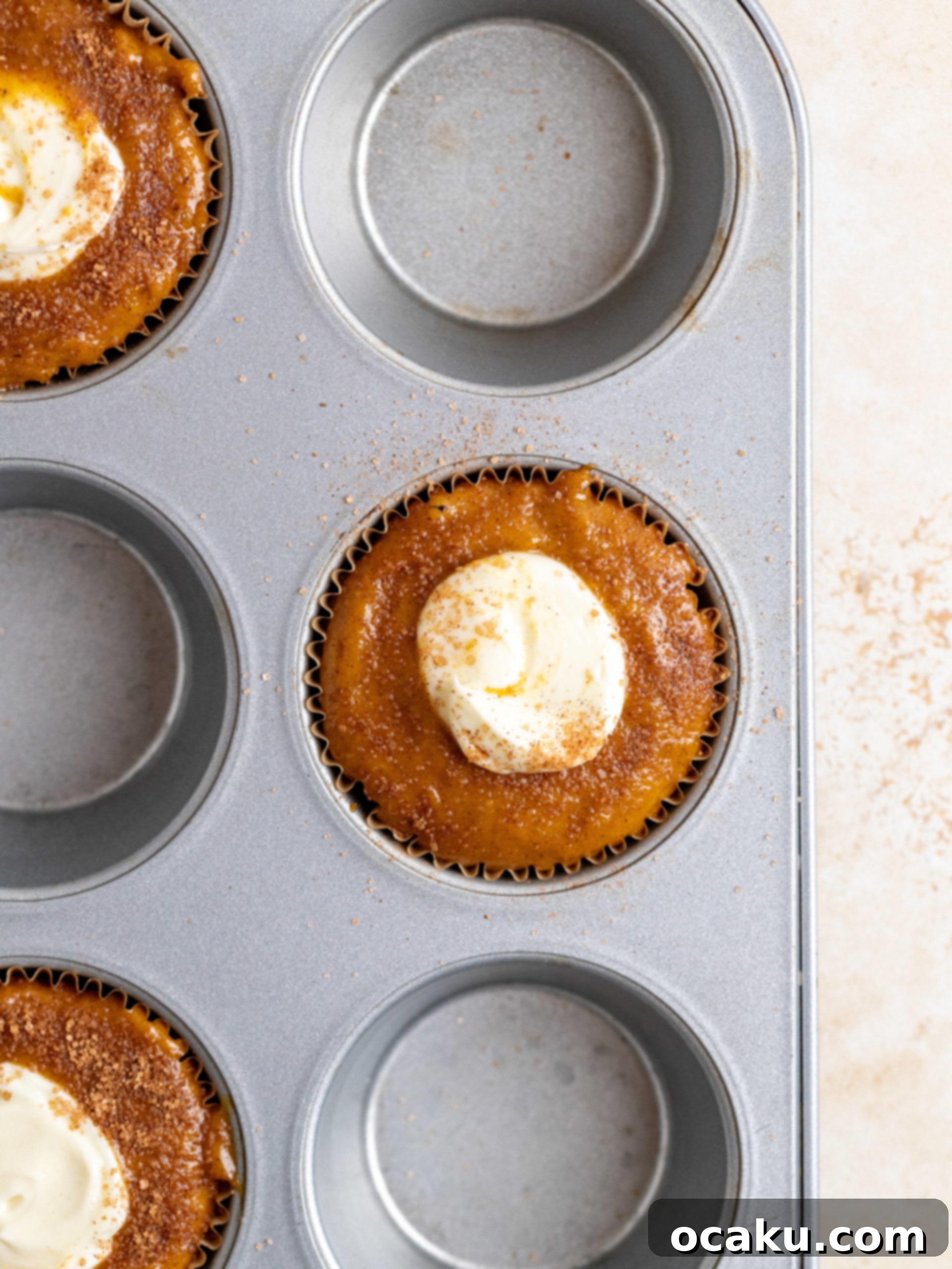 Pumpkin cream cheese muffins topped with cinnamon sugar before baking.