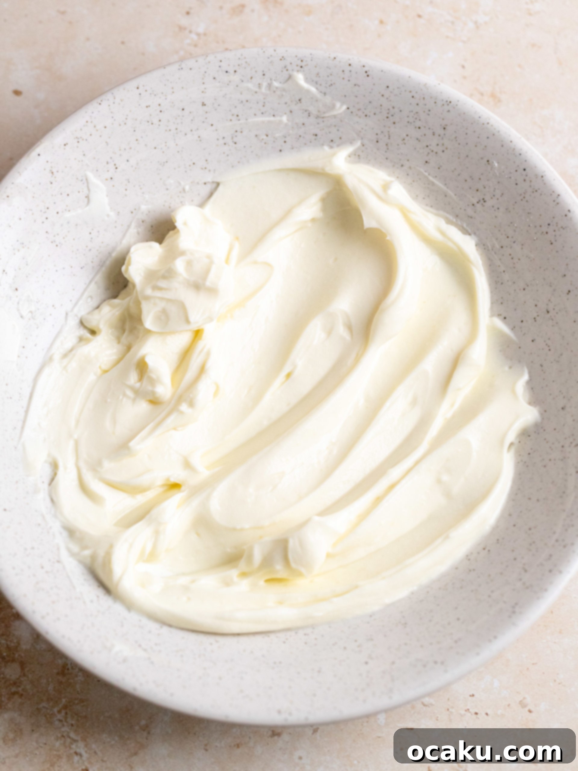 Cream cheese filling being spread over the pumpkin cake batter in the pan.