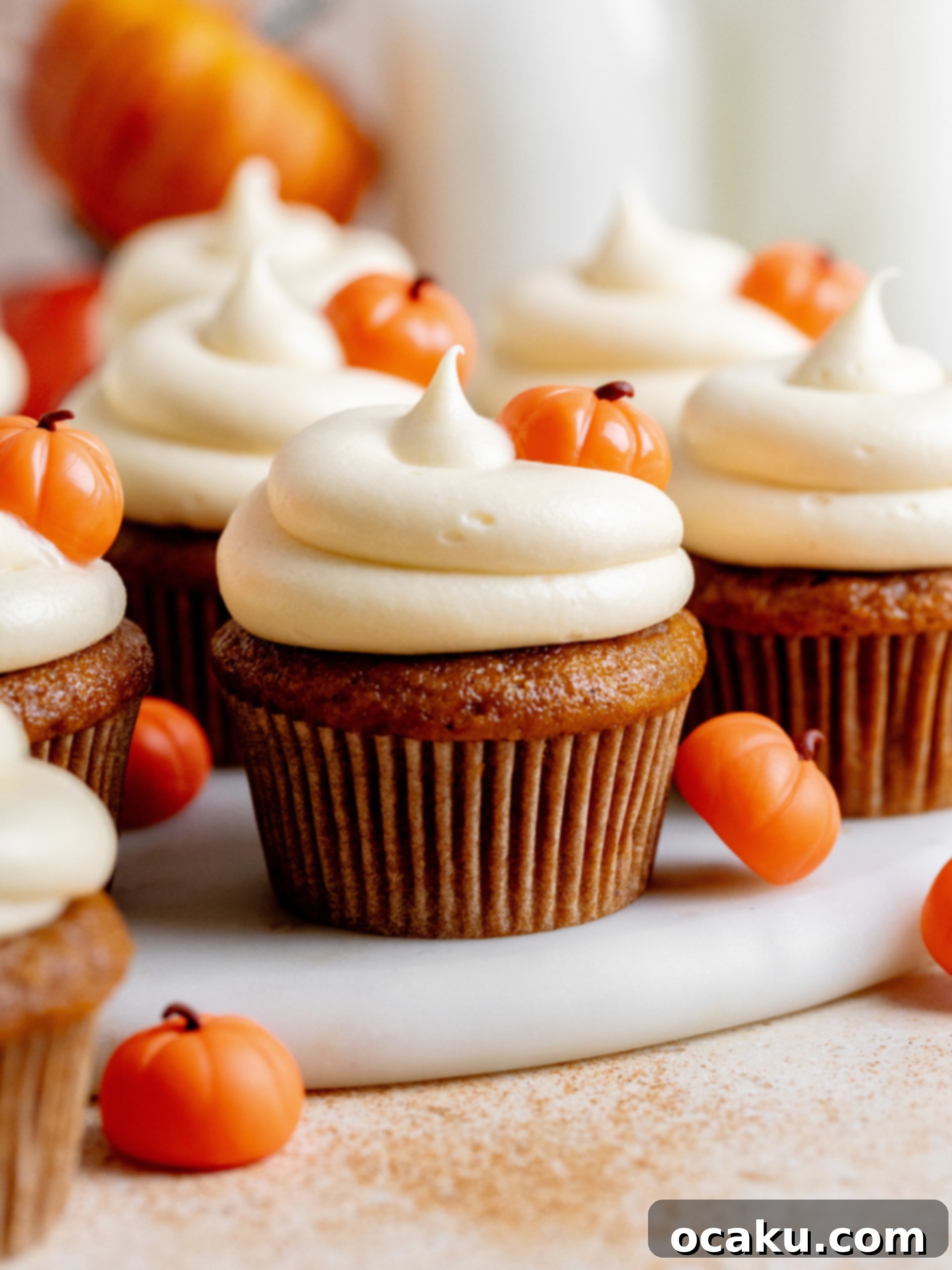 Pumpkin cupcakes being frosted with a piping bag.