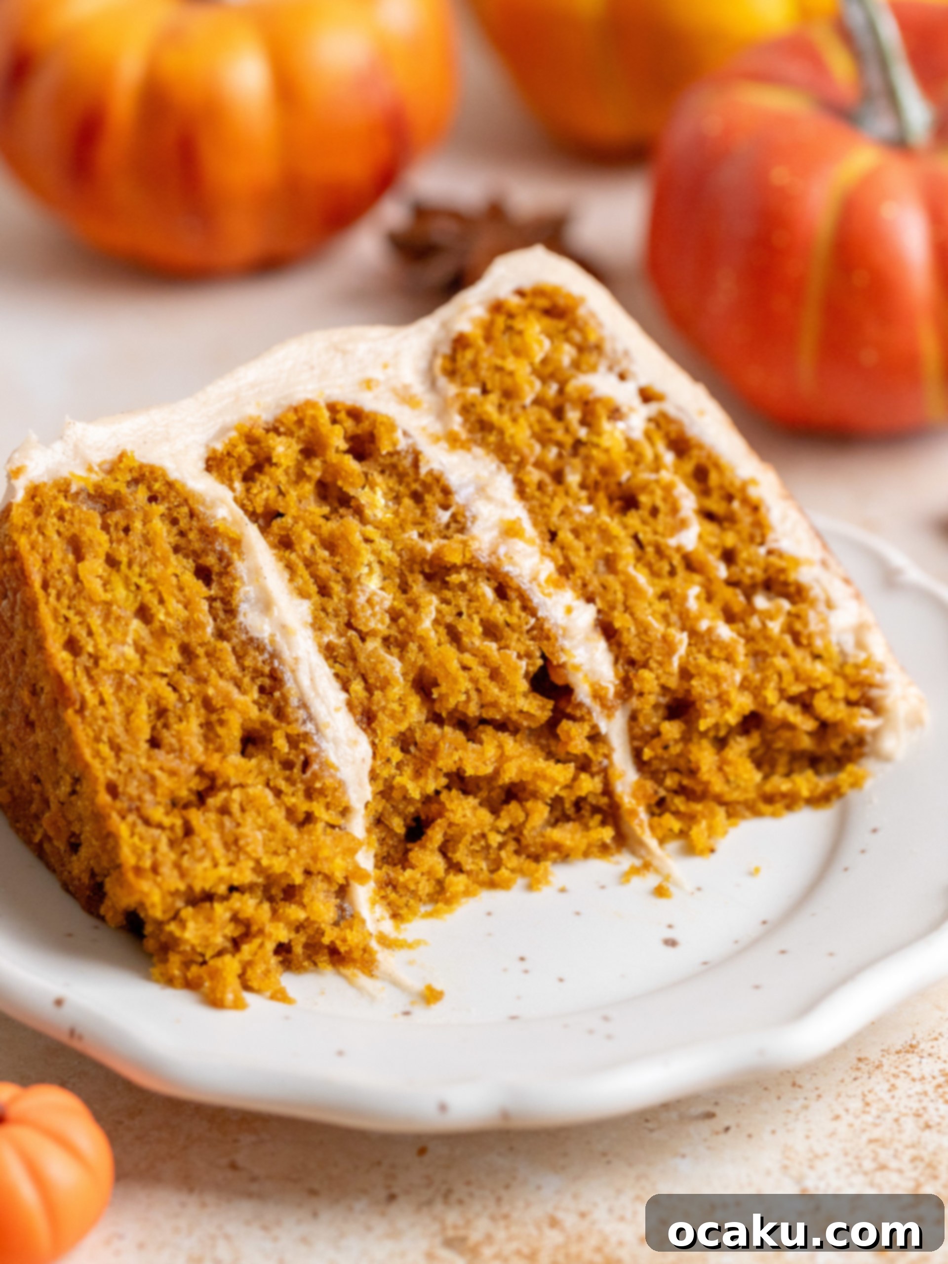 A beautifully frosted pumpkin layer cake adorned with mini pumpkins and cinnamon dusting, ready to be served