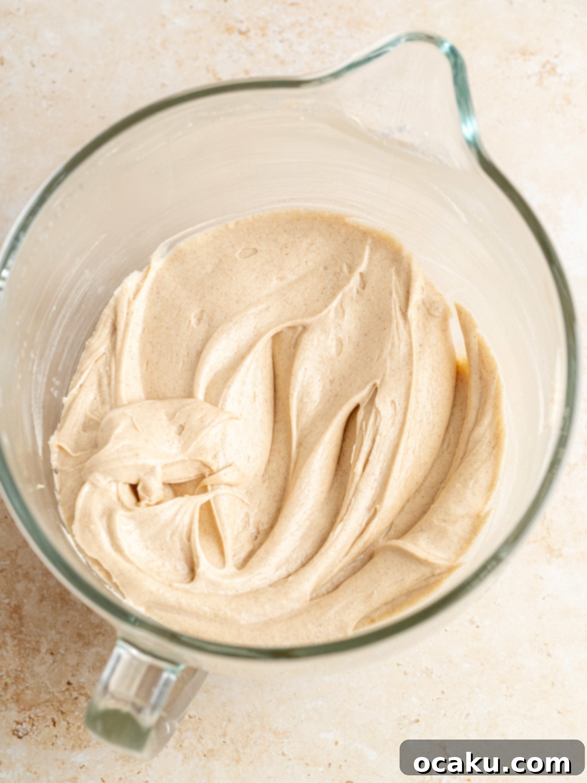 Spreading the first layer of cinnamon cream cheese frosting on a pumpkin cake layer
