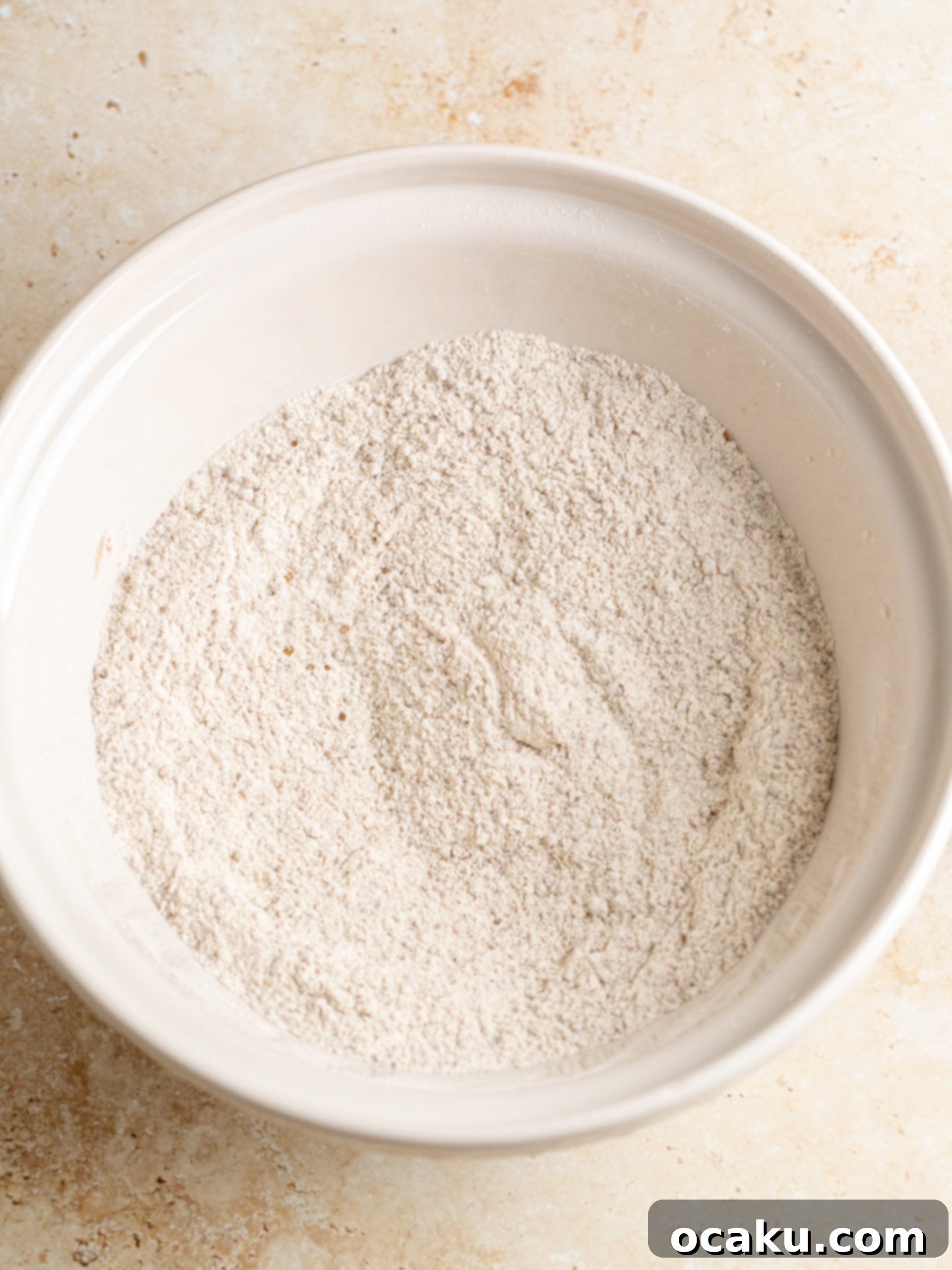 Step-by-step image showing the dry ingredients mixed in a bowl for the apple cake batter.