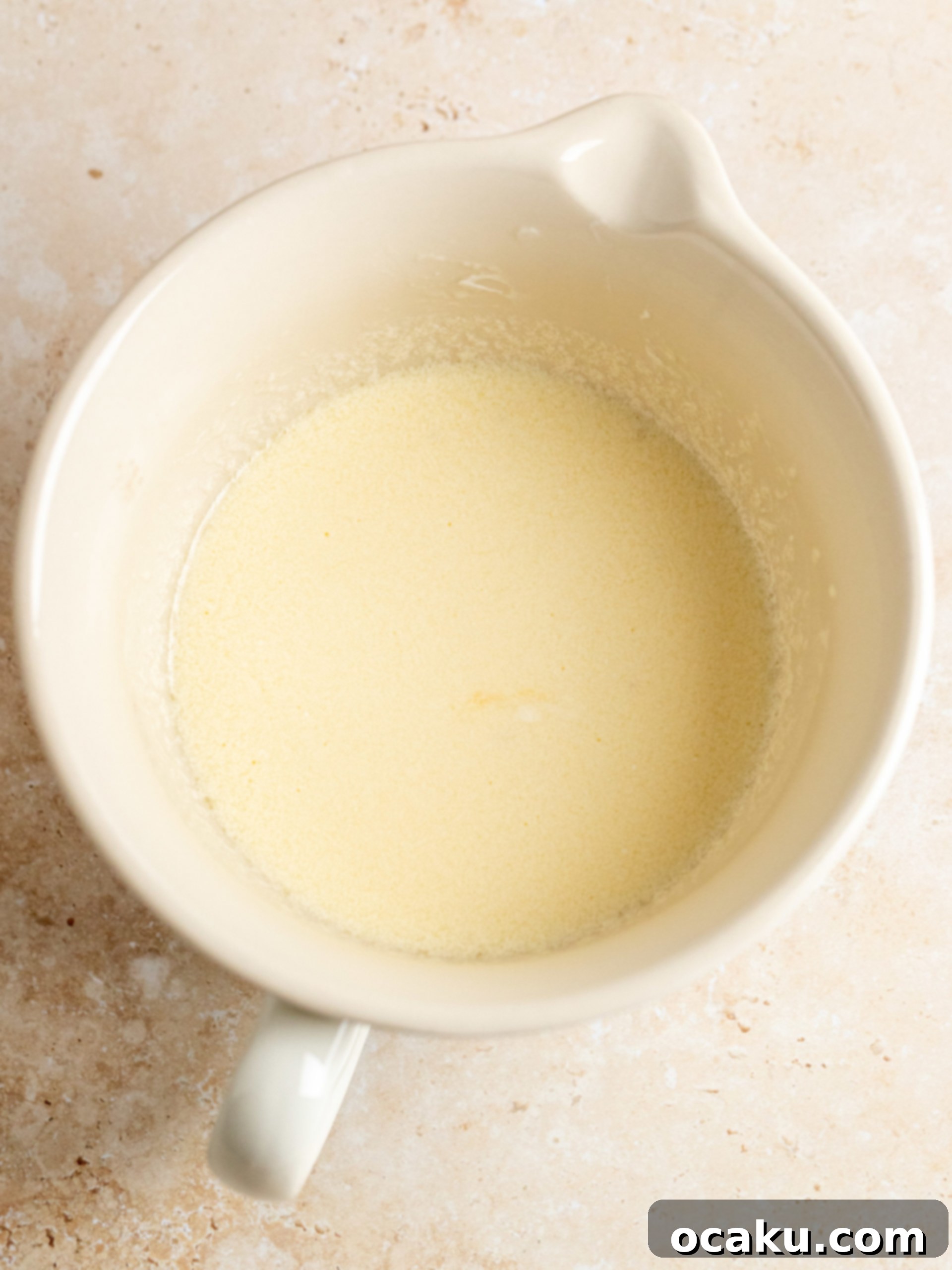 Step-by-step image showing the wet ingredients whisked smoothly in a separate bowl for the apple cake.