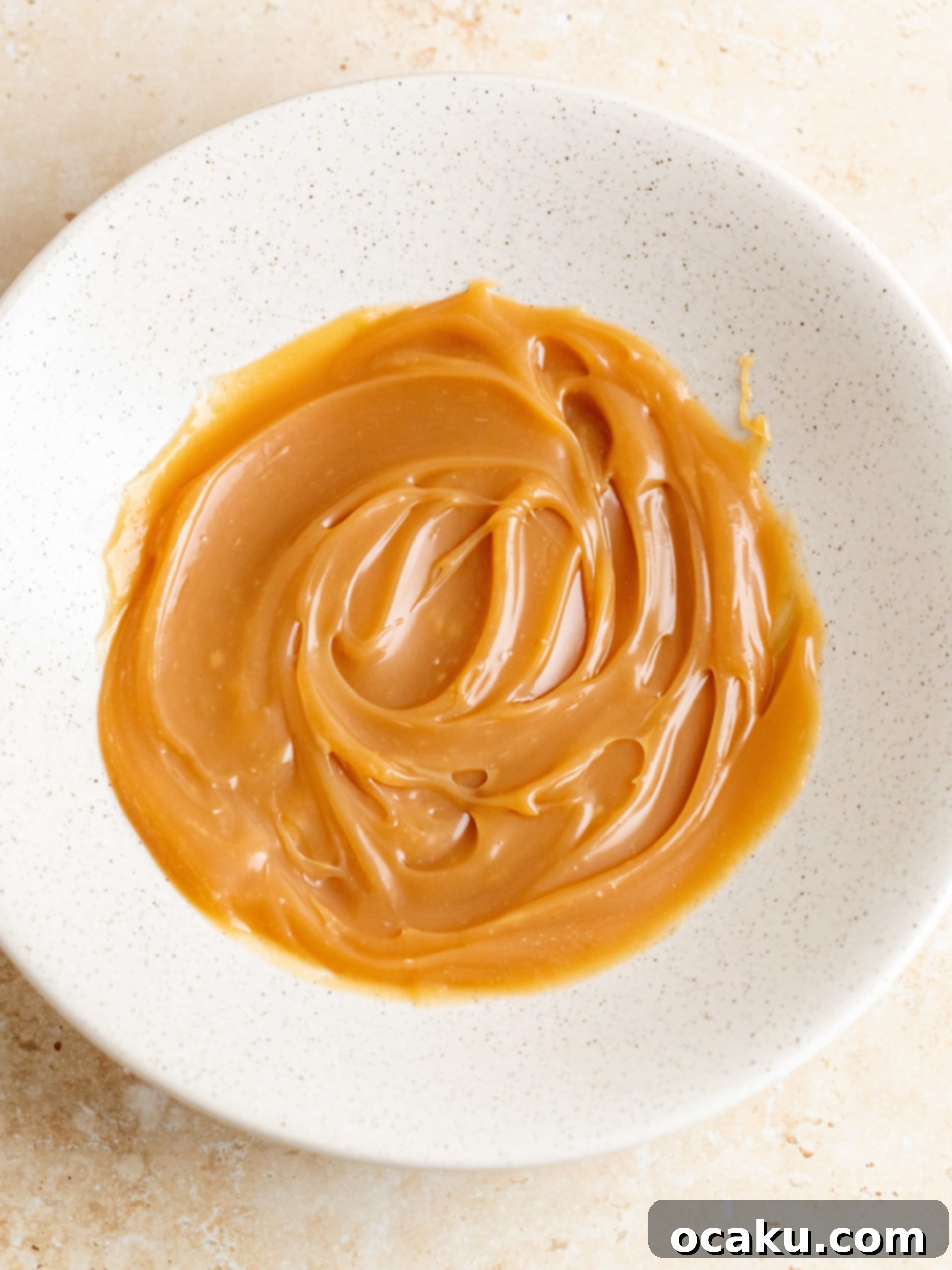 Step-by-step image showing a generous amount of caramel sauce being drizzled over the frosted apple cake.