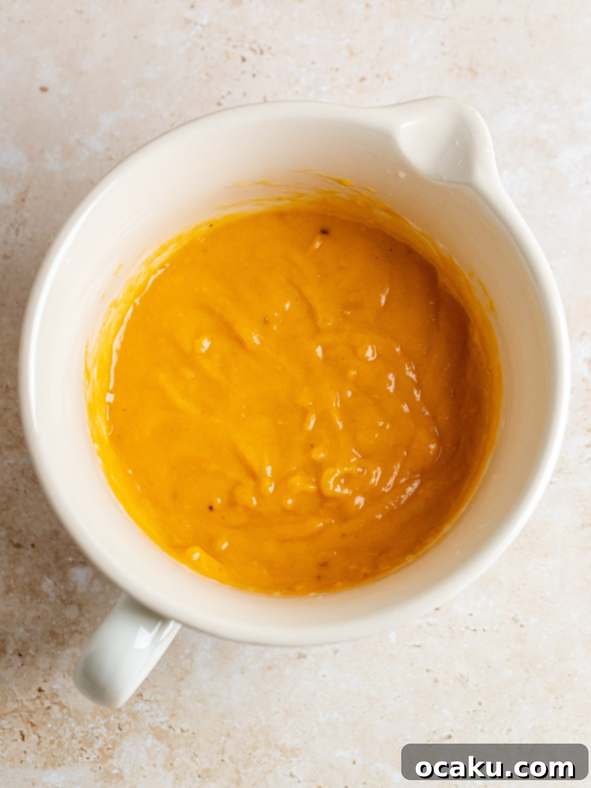 Combining wet ingredients in a separate bowl for sweet potato bread.