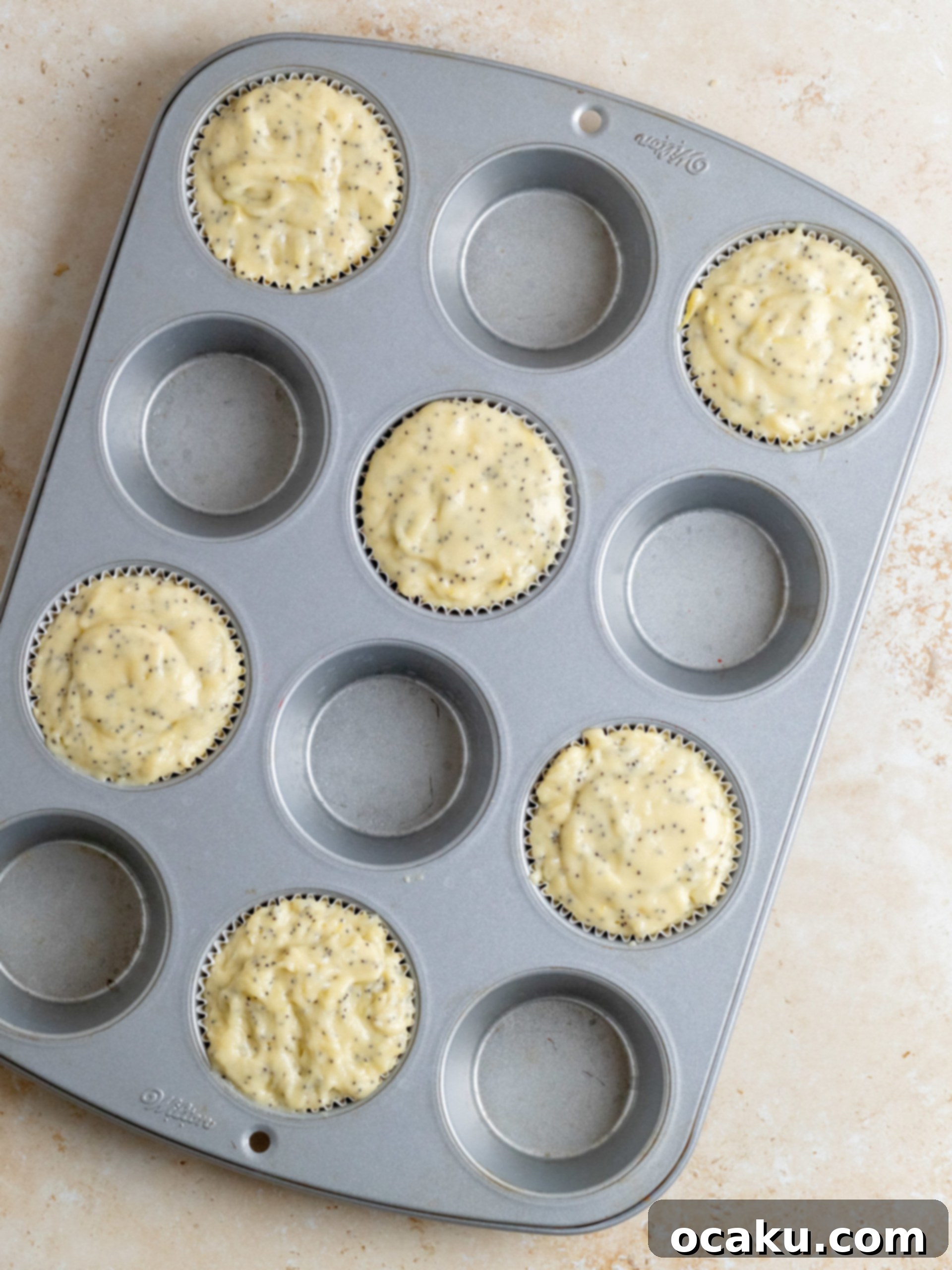 Muffin batter resting in a bowl, covered with plastic wrap, before baking.