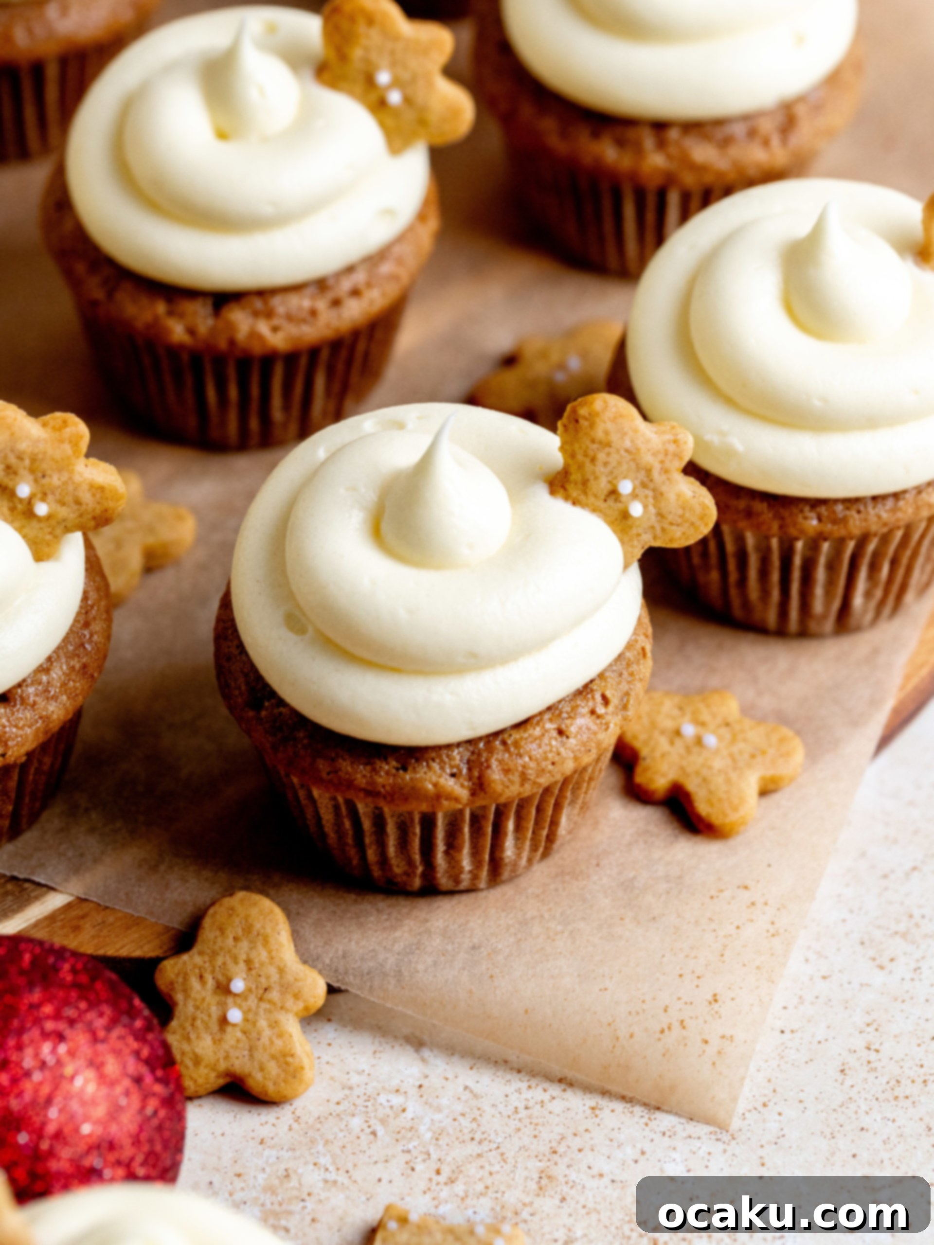 Two gingerbread cupcakes with cream cheese frosting on a festive background.