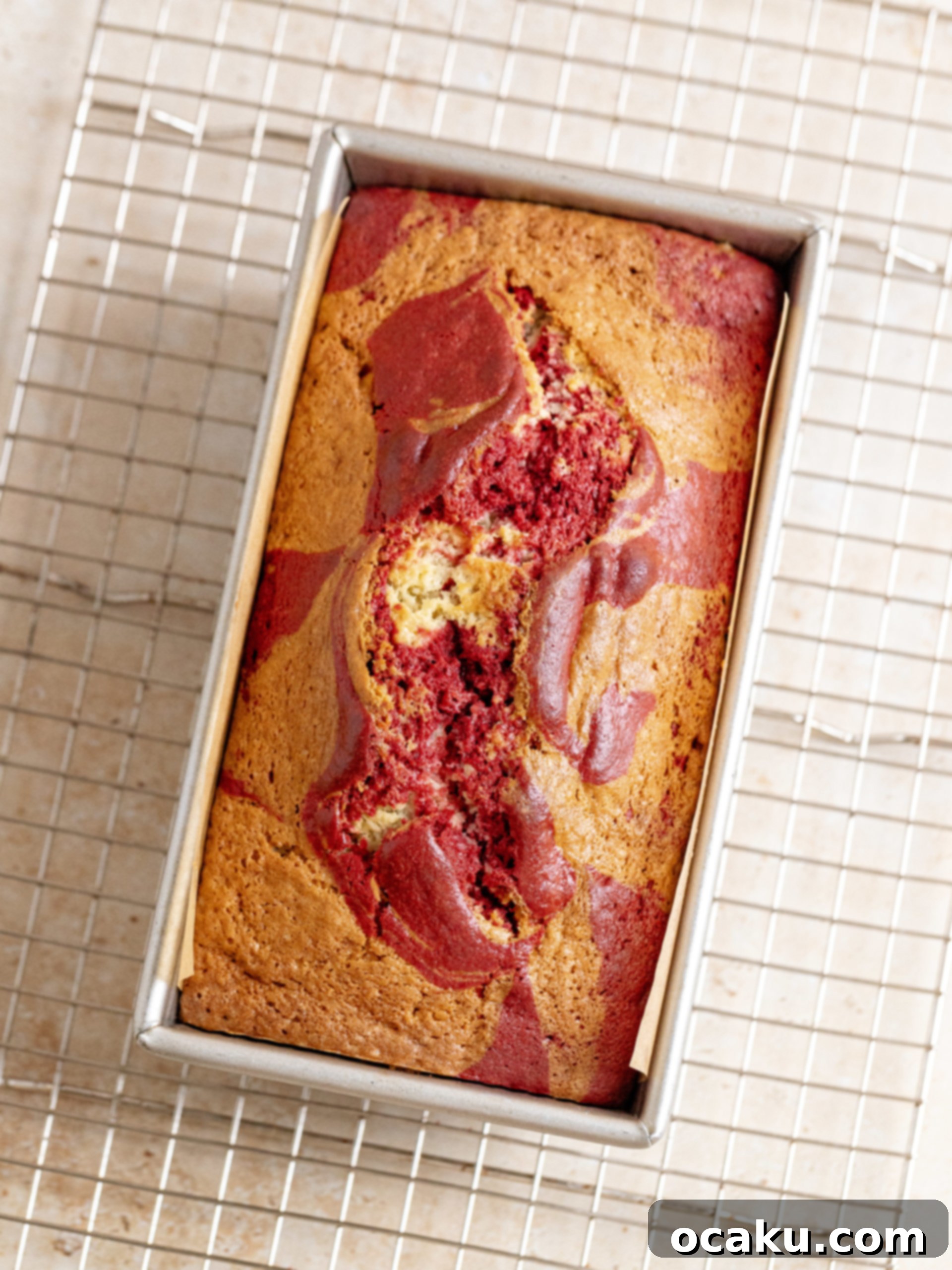 Cream cheese frosting being spread on a red velvet loaf cake.