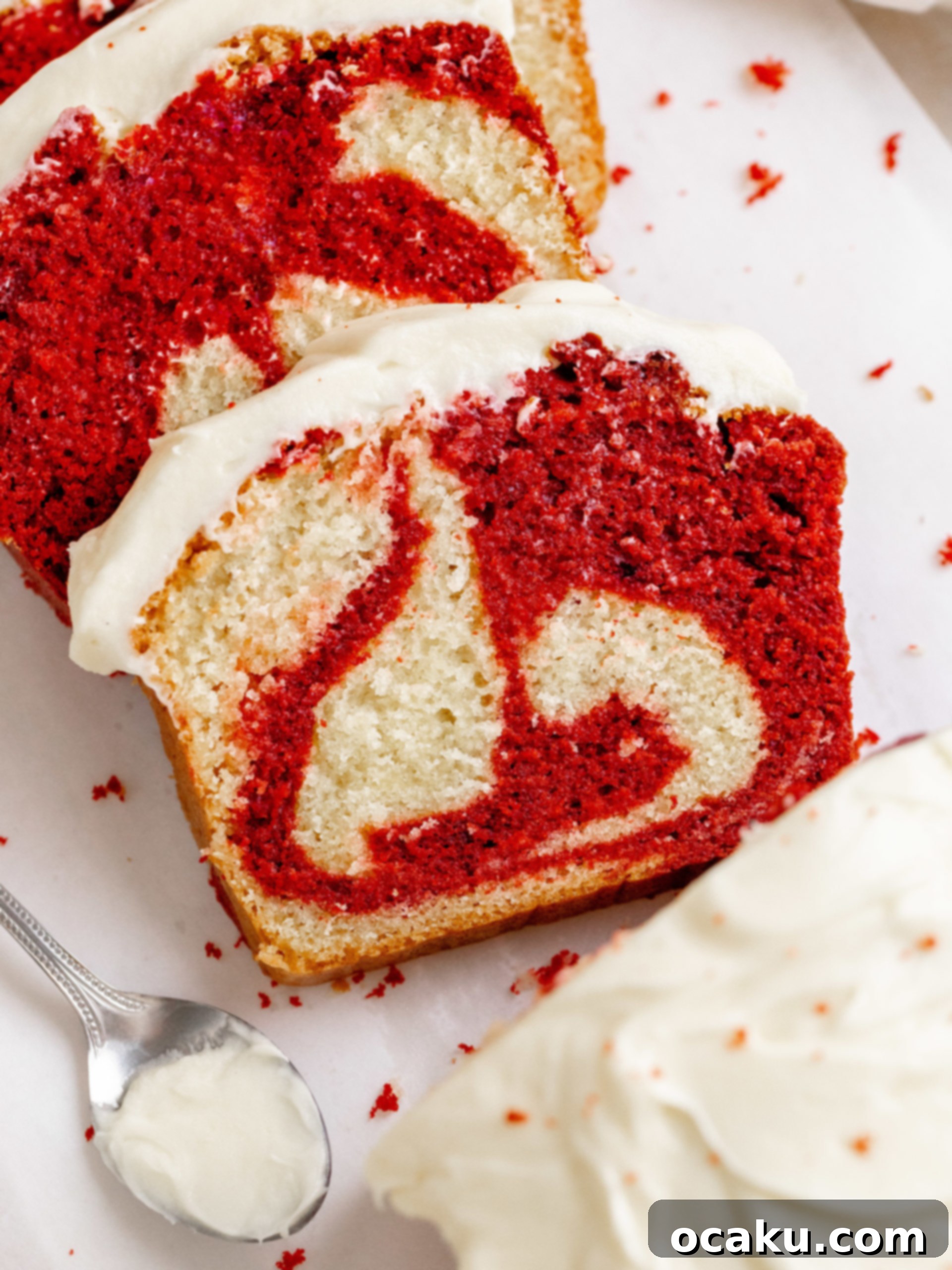 A beautifully sliced red velvet loaf cake with cream cheese frosting, showing the swirl.