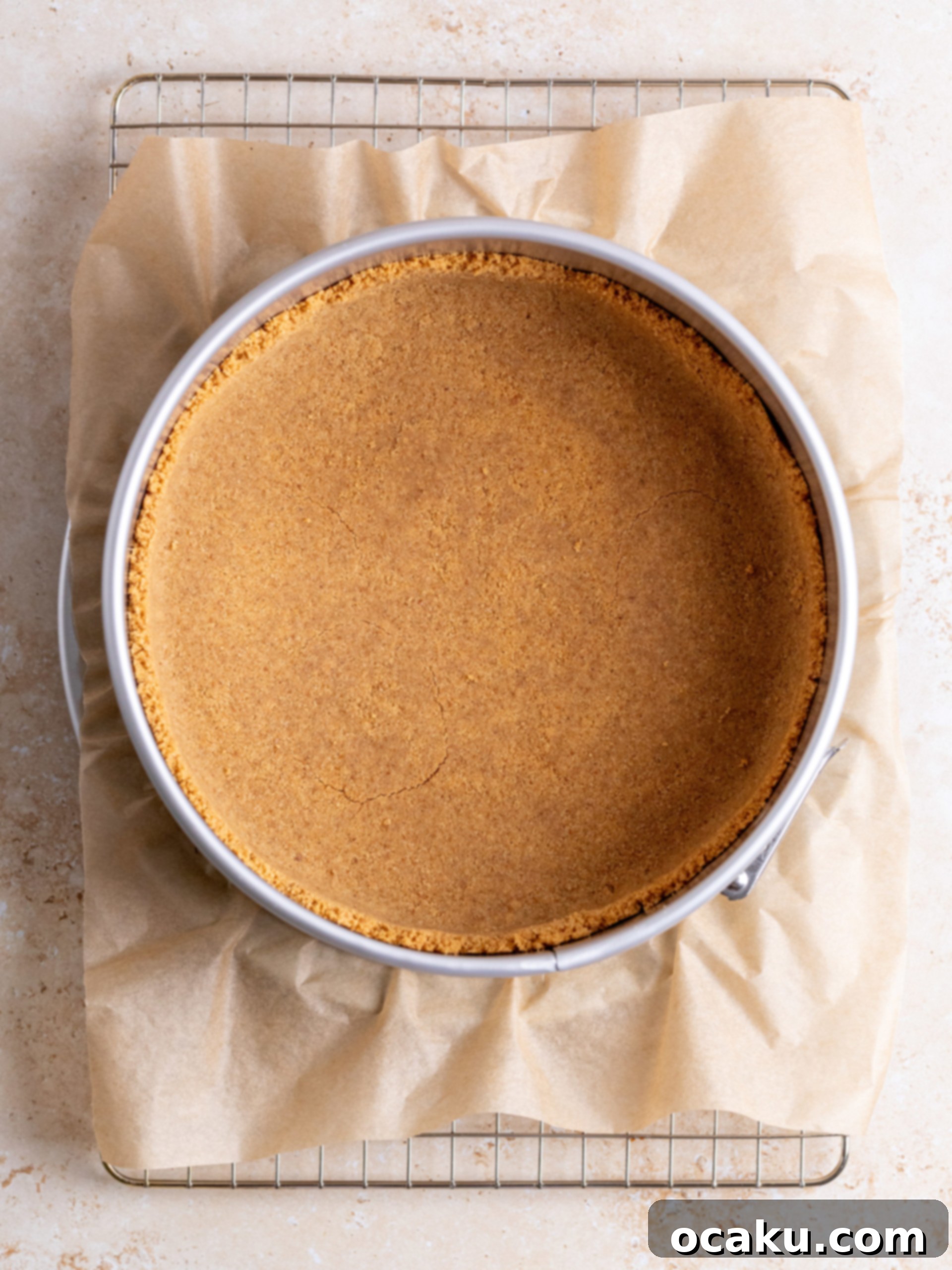 Cookie crumbs being pressed into a springform pan for the cheesecake crust.