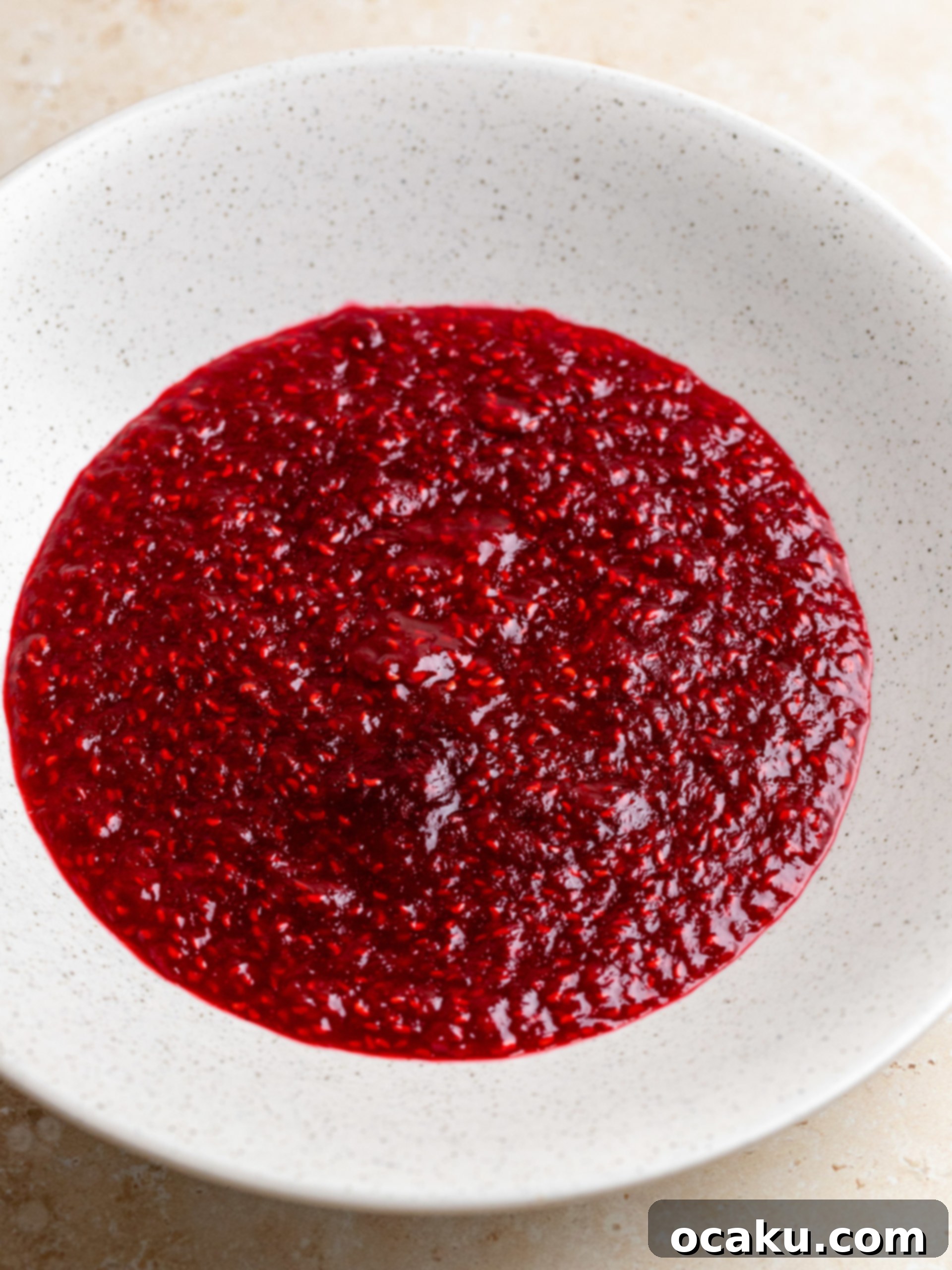 The vibrant green pistachio cake batter being poured into prepared round baking pans.