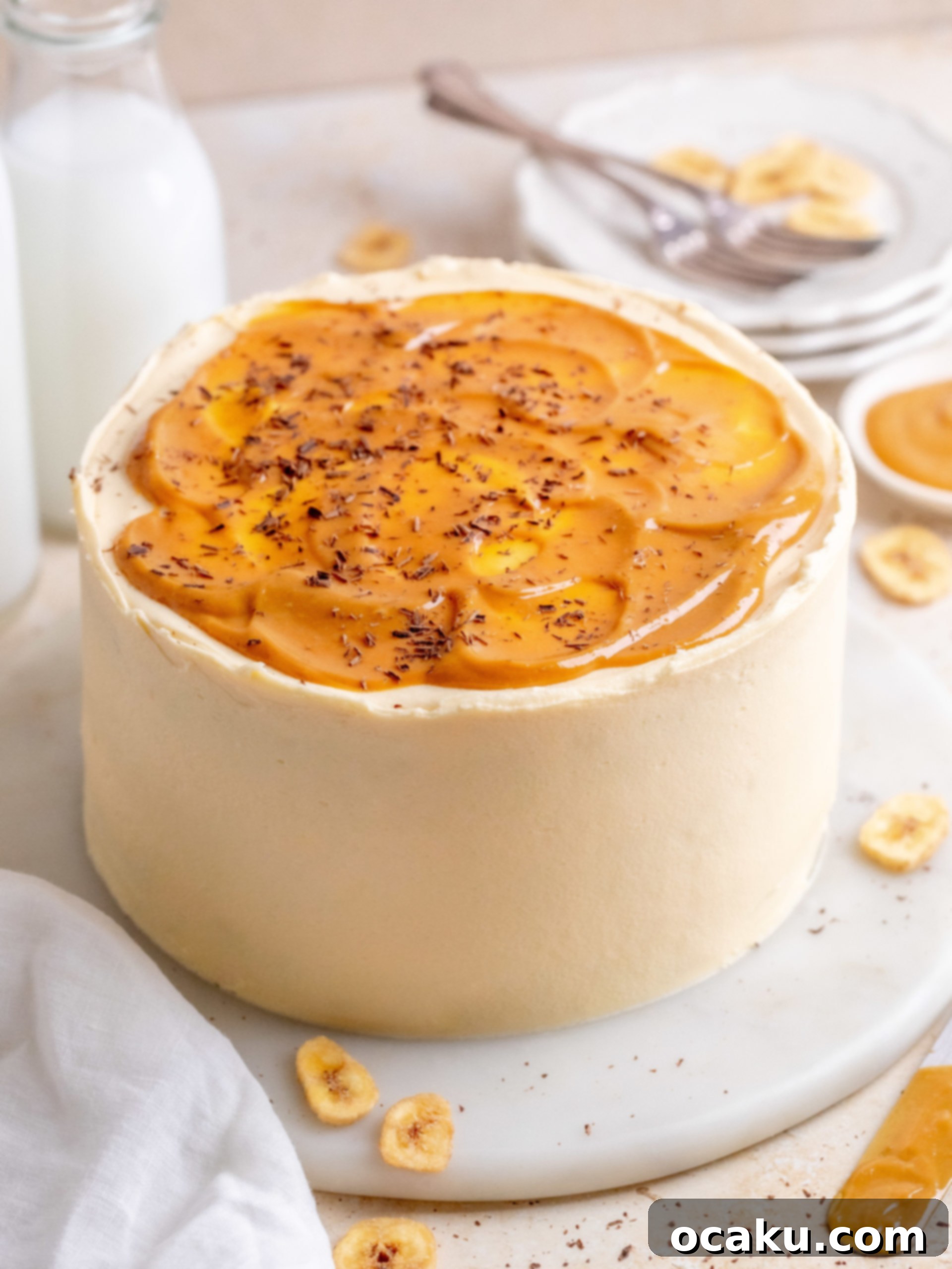 A stunning Banoffee Layer Cake with visible banana, caramel, and chocolate layers, topped with dulce de leche drizzle and chocolate shavings.