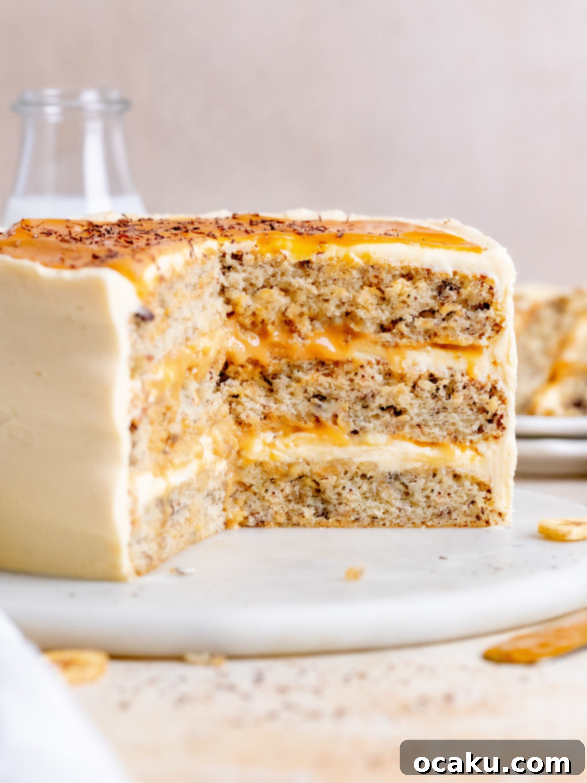 A close-up of a perfectly cut slice of Banoffee Layer Cake, revealing the moist banana cake, rich dulce de leche, and fresh banana layers.
