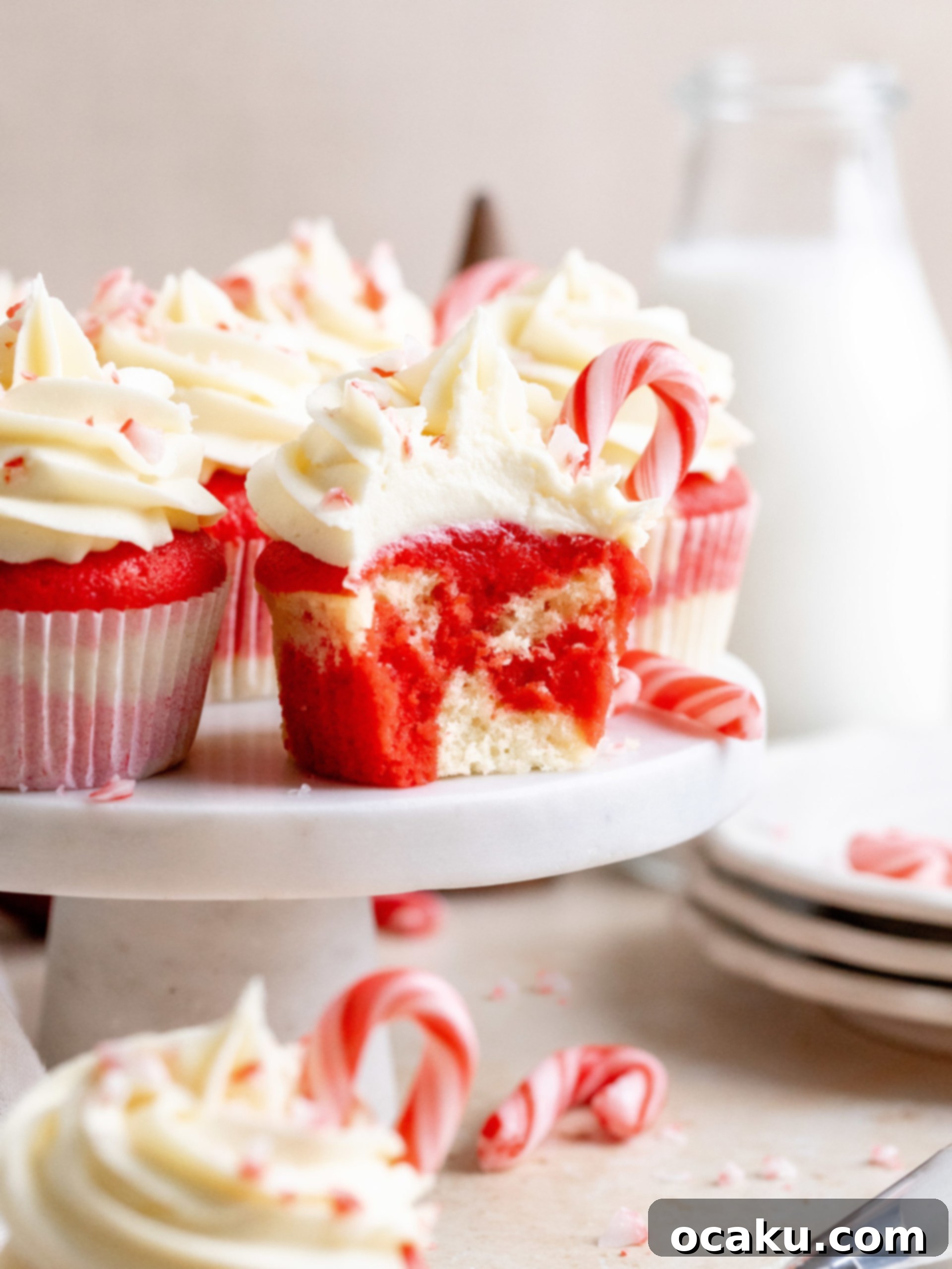 A close-up of a festive white chocolate peppermint cupcake on a wooden surface.
