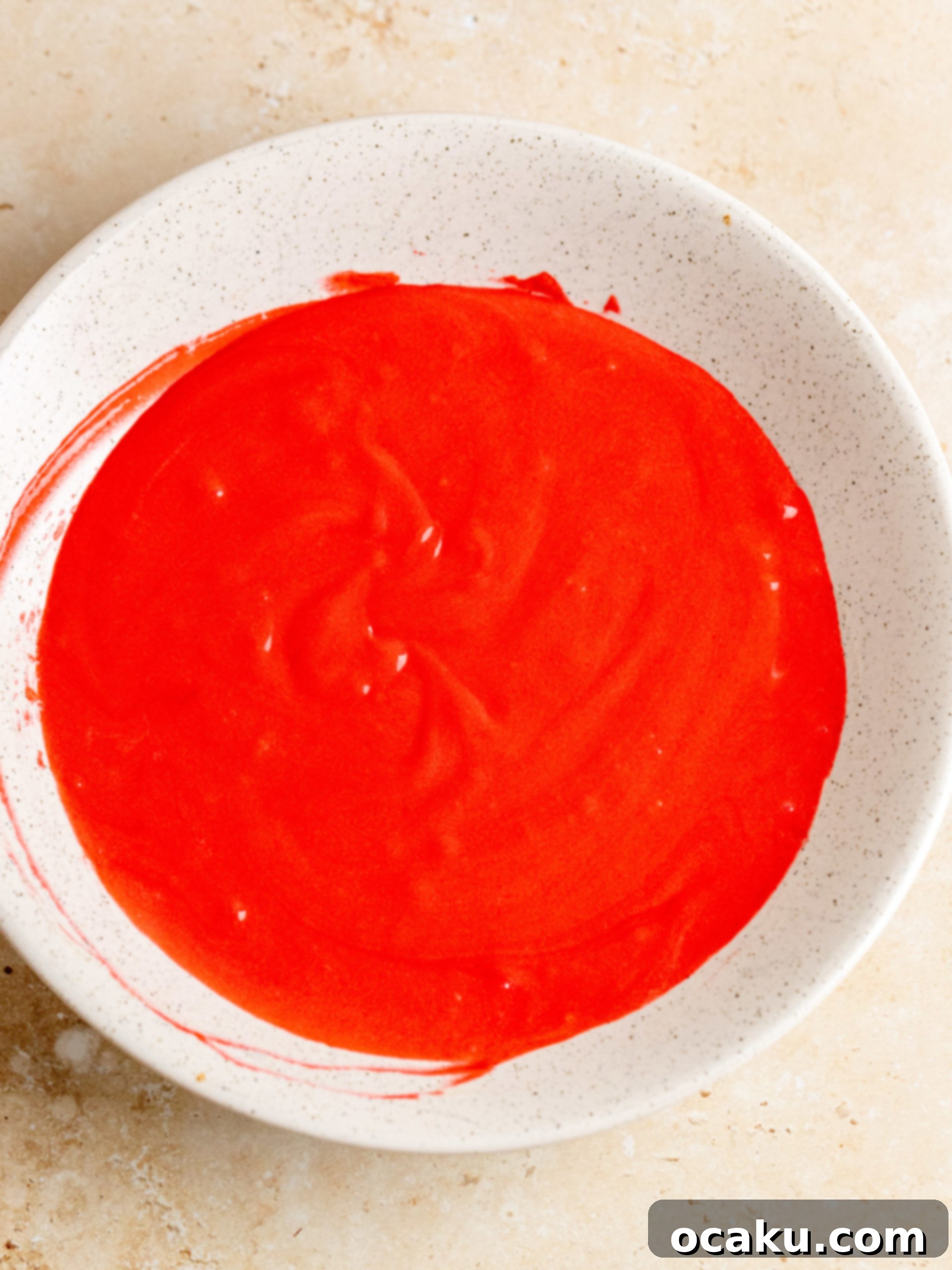 Red food coloring being added to a portion of cupcake batter.