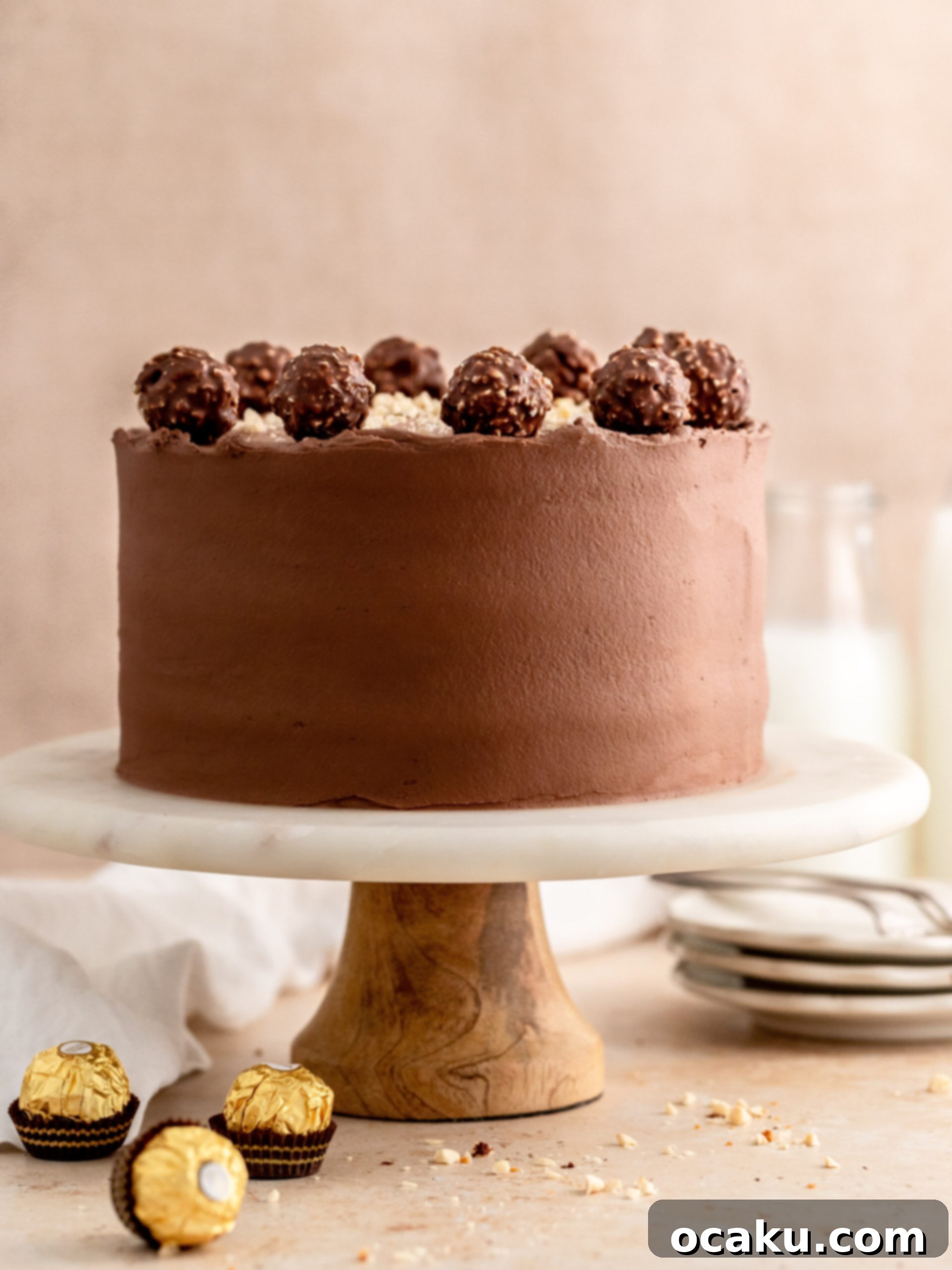 Ferrero Rocher Chocolate Hazelnut Cake 2 A stunning slice of Ferrero Rocher cake with layers of chocolate cake, Nutella buttercream, and chopped Ferrero Rochers and hazelnuts.
