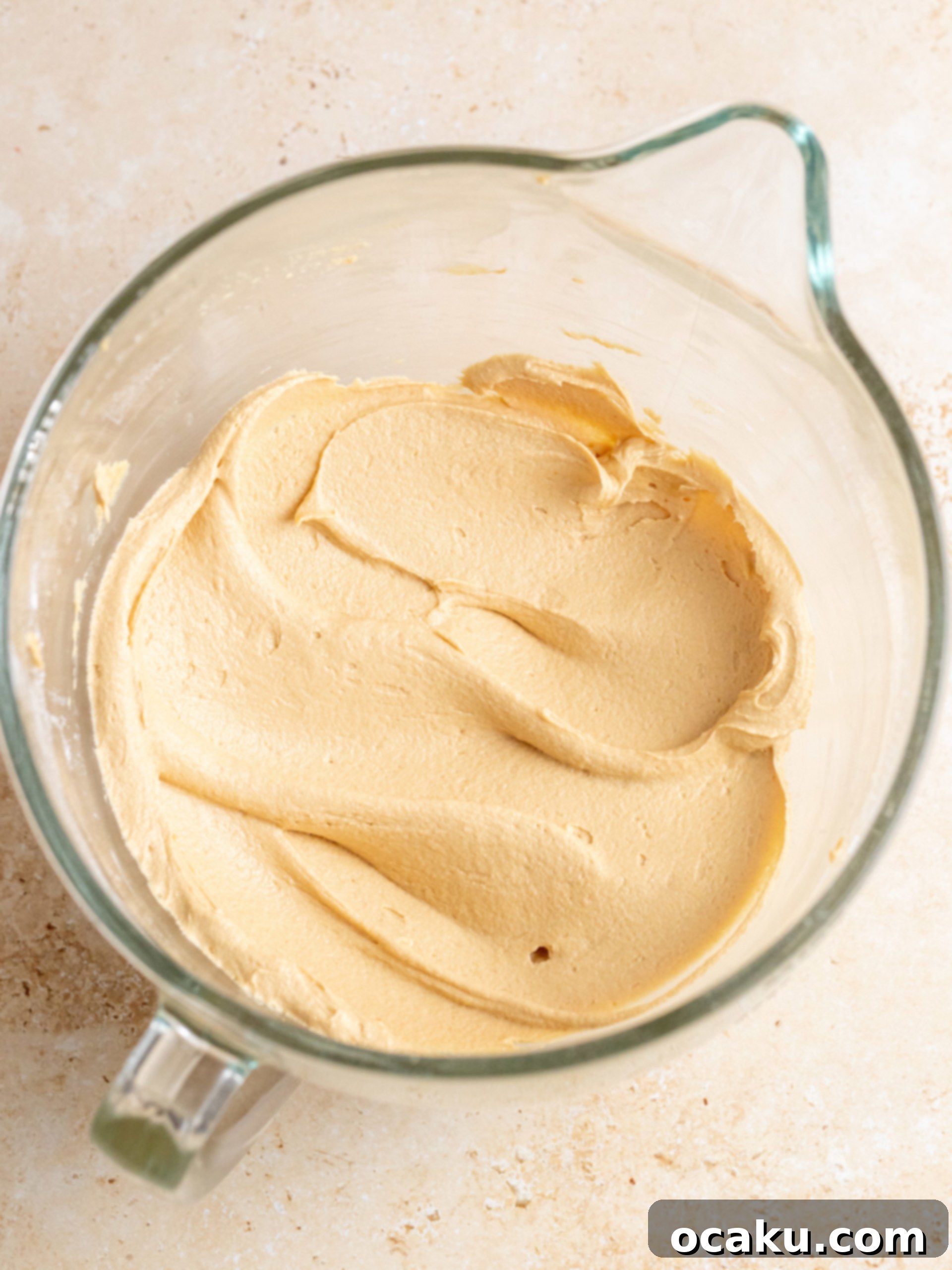 Step-by-step image showing melted Biscoff spread being poured into the concave of the buttercream.