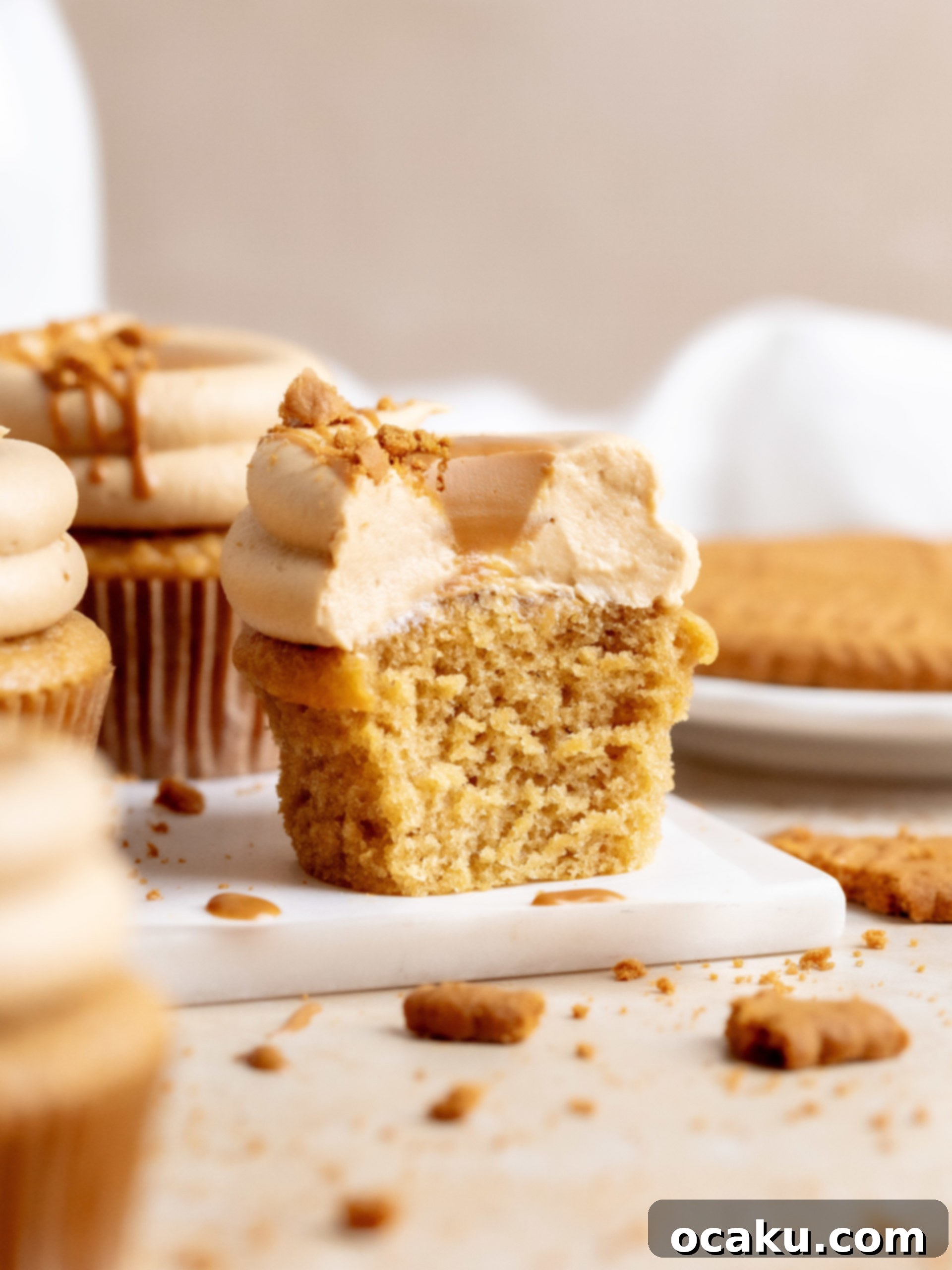A Biscoff cupcake with a spoon, highlighting the creamy frosting and cookie crumbs.