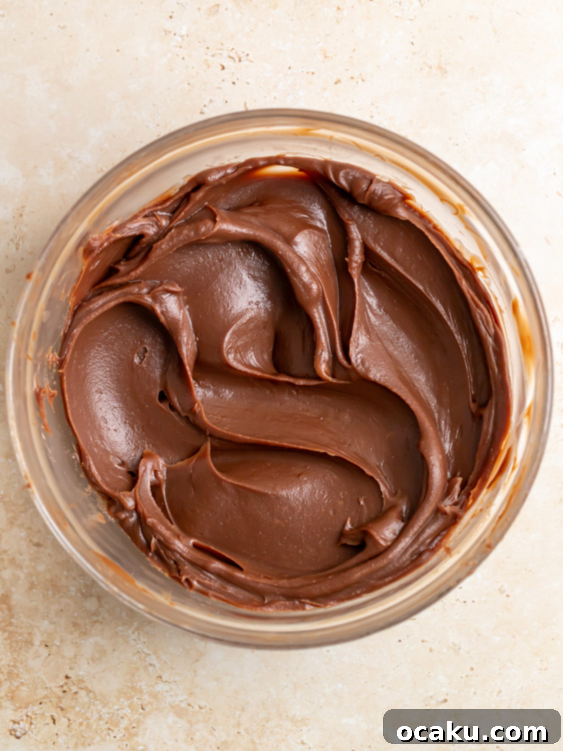 Close-up of melted chocolate chips in a bowl with hot cream, showing the start of ganache making.