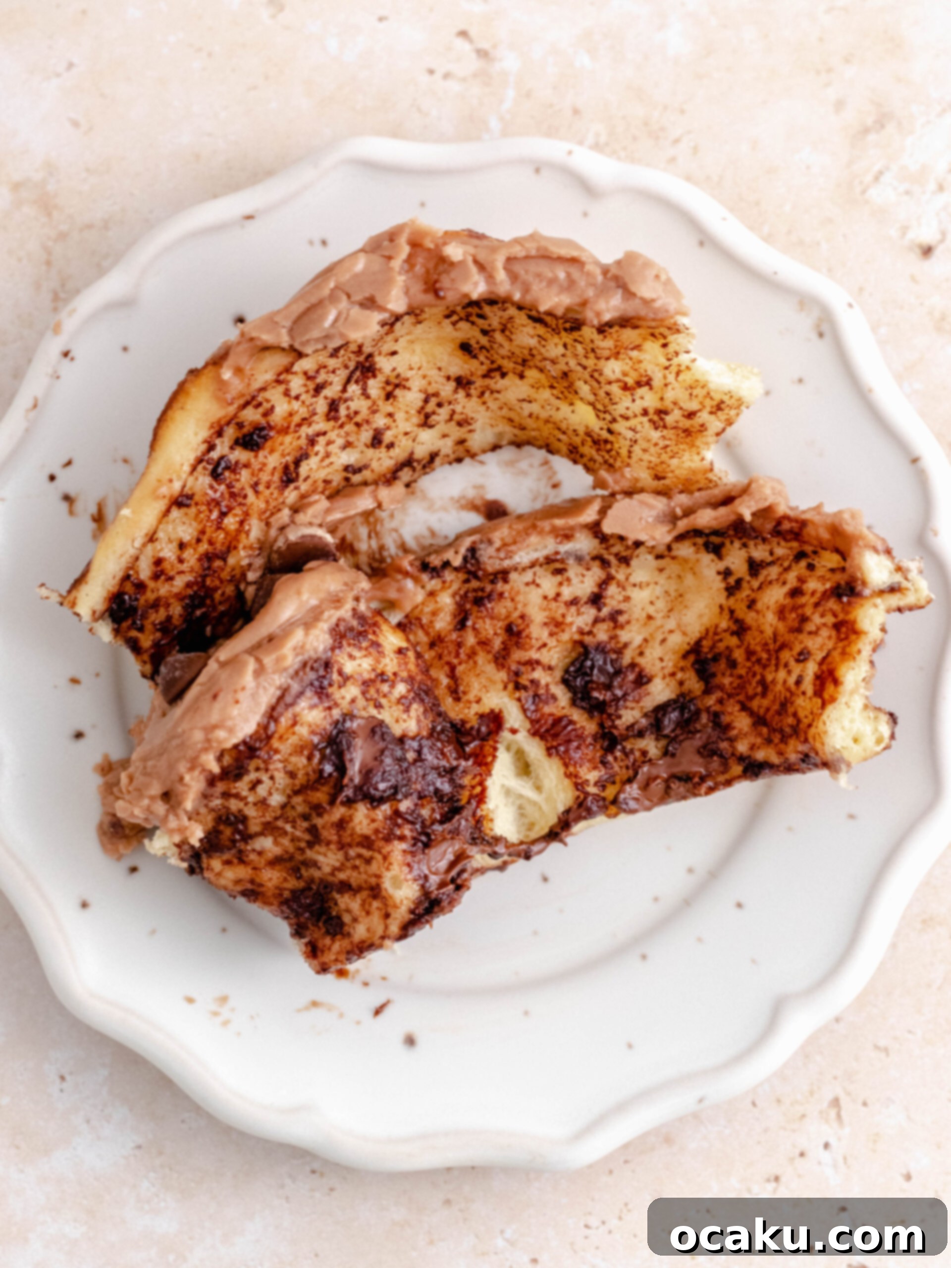 Decadent Nutella Swirls 7 Two soft Nutella rolls on a white plate, one bitten to show the gooey chocolate chip and Nutella filling.