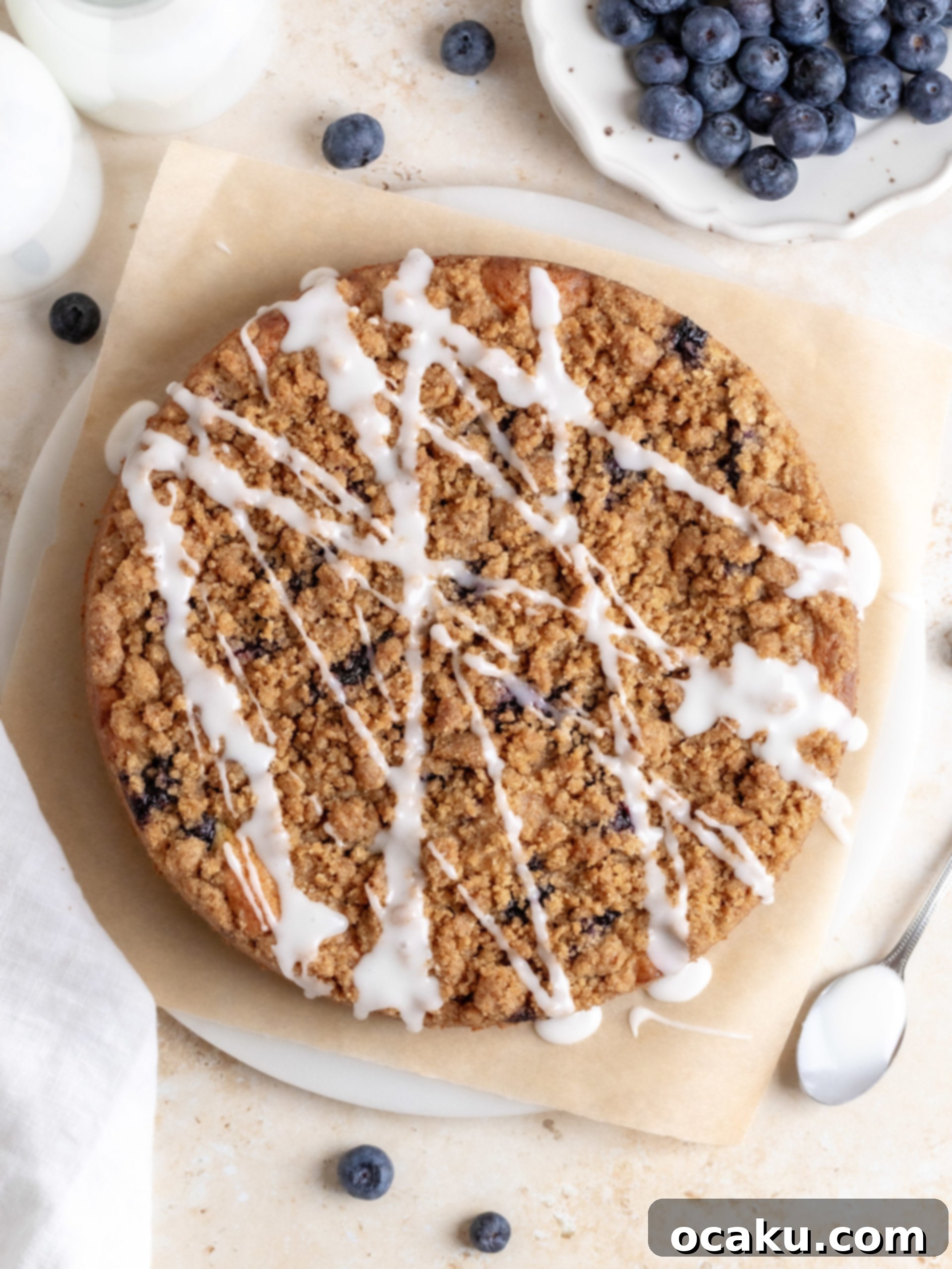 Lemon glaze being drizzled over the cooled blueberry coffee cake, adding a shiny, zesty finish.