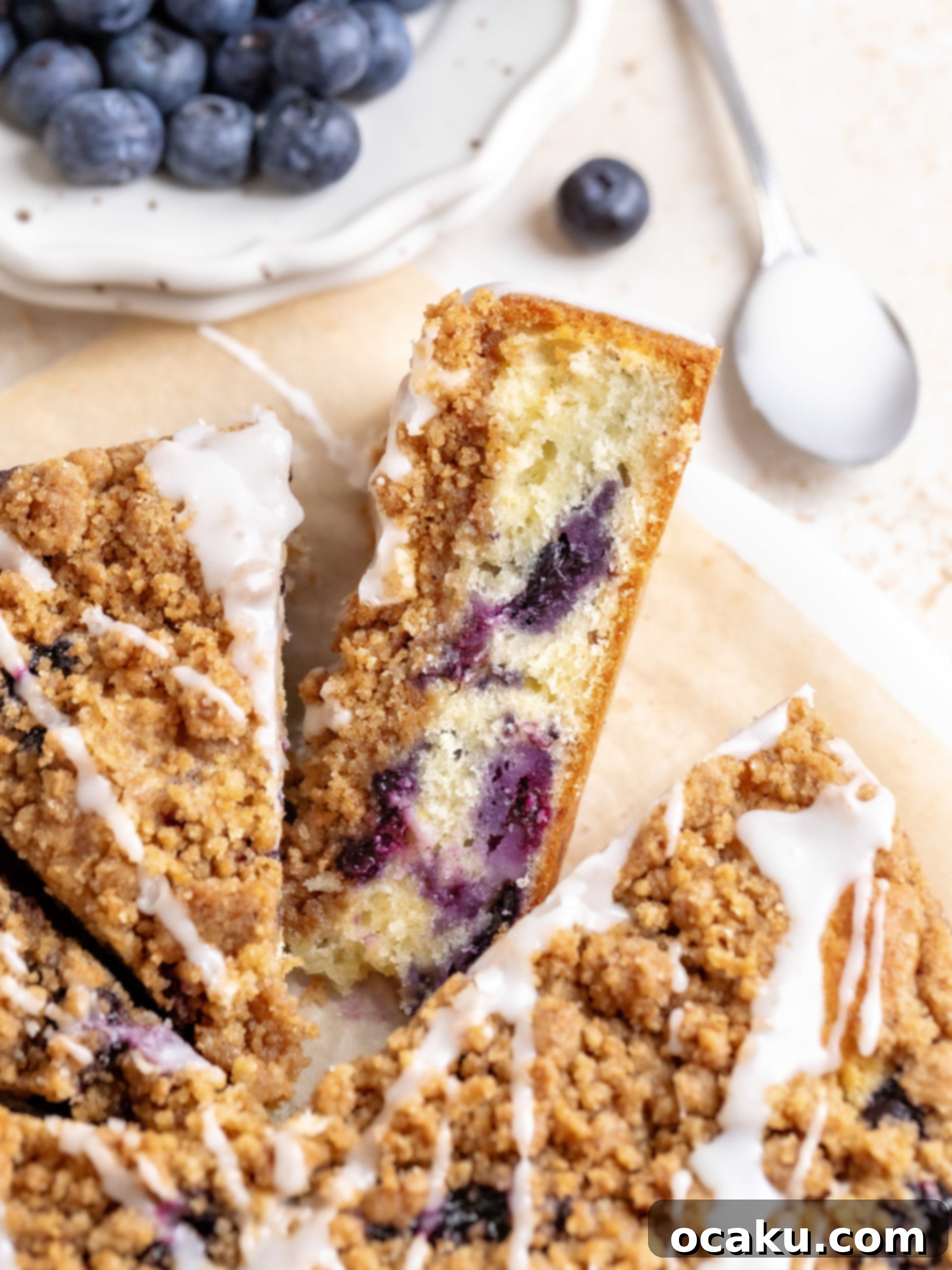 A slice of blueberry coffee cake with lemon glaze, accompanied by a cup of coffee, ready to be enjoyed.