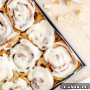 Close-up of a single apple pie cinnamon roll with frosting.