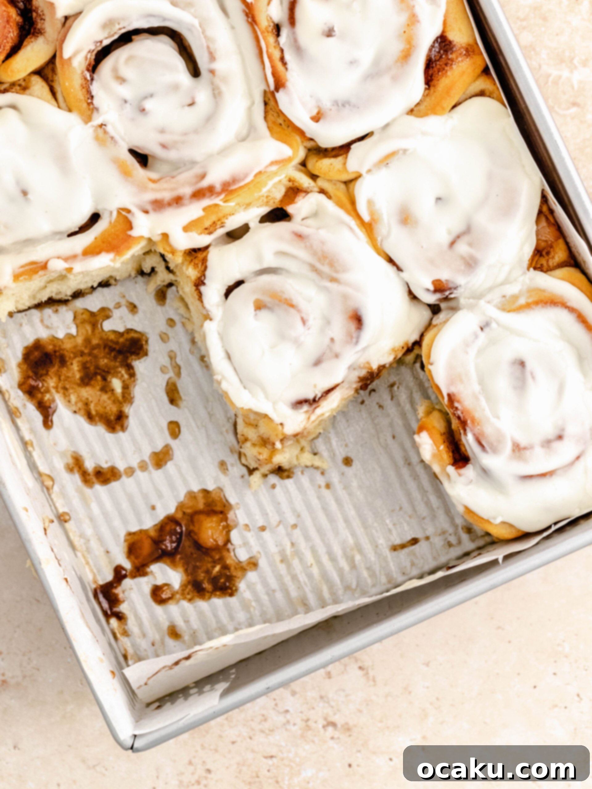 Freshly baked and frosted cinnamon rolls with apple pie filling, pulled from the baking tray.