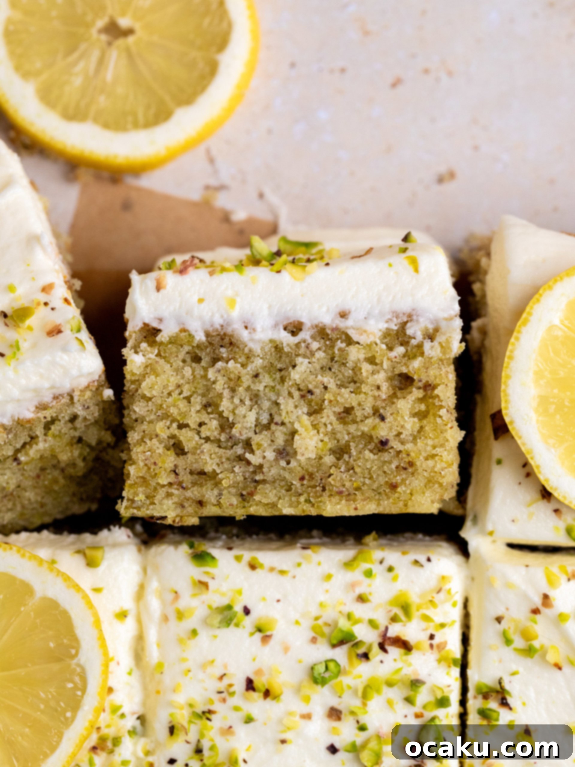 Aperol Spritz Cheesecake Close-up of a slice of soft lemon pistachio cake, showing its moist green crumb and a generous layer of white chocolate buttercream.