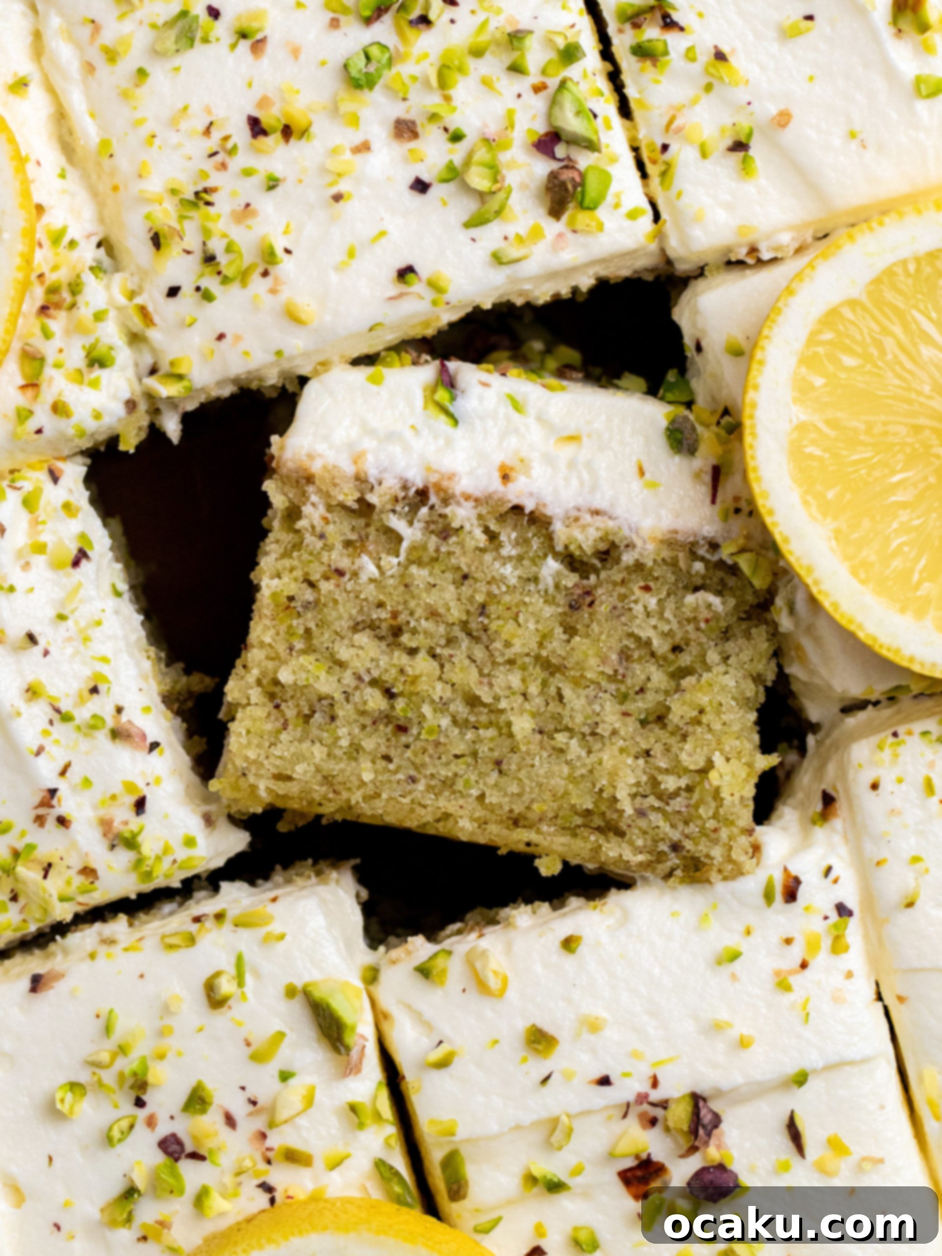 Zesty Lemon Pistachio Cake 5 A large rectangular lemon pistachio sheet cake frosted with white chocolate buttercream and topped with chopped pistachios.