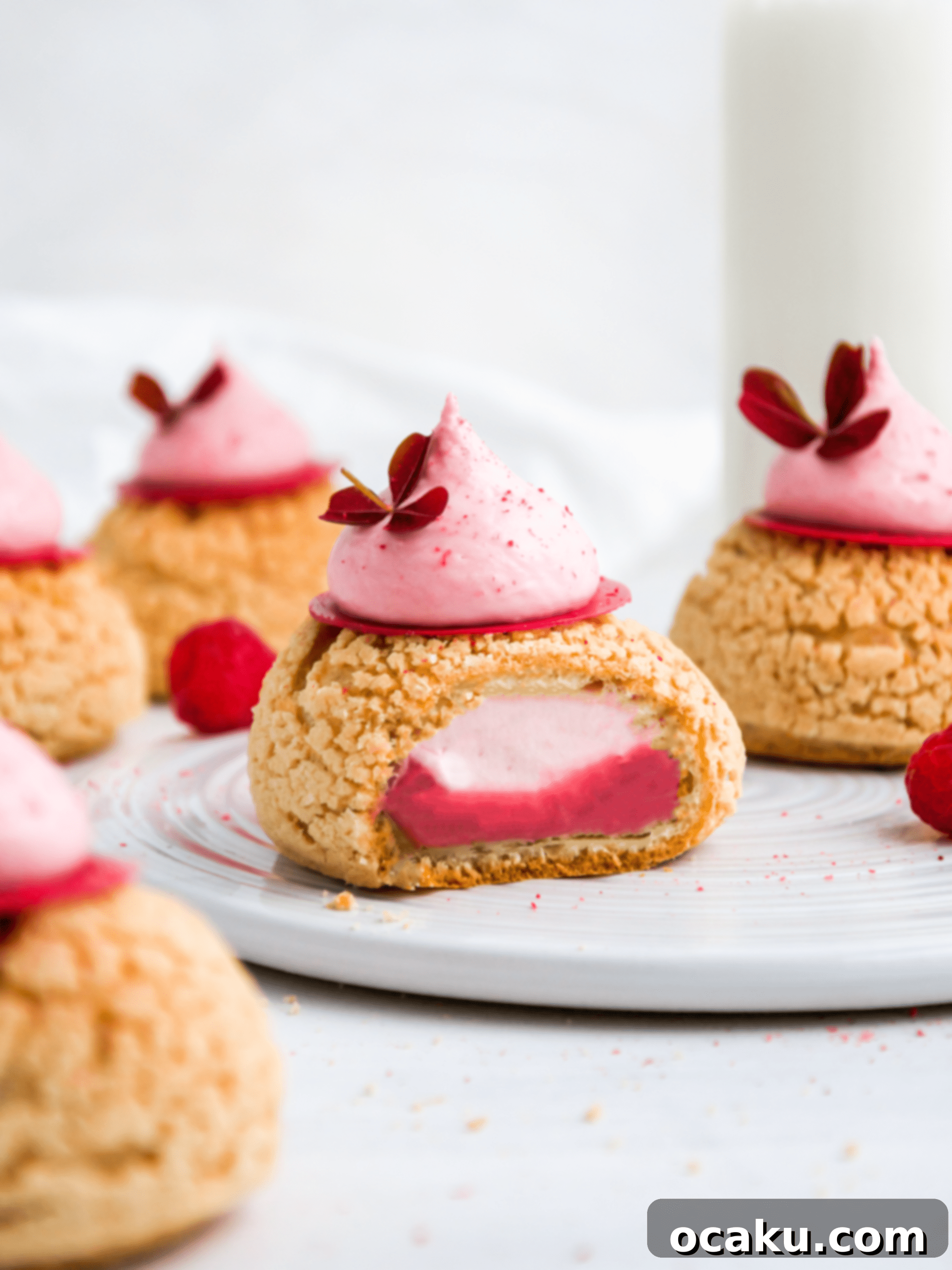 A perfectly sliced Raspberry Choux au Craquelin revealing its creamy raspberry and white chocolate filling.