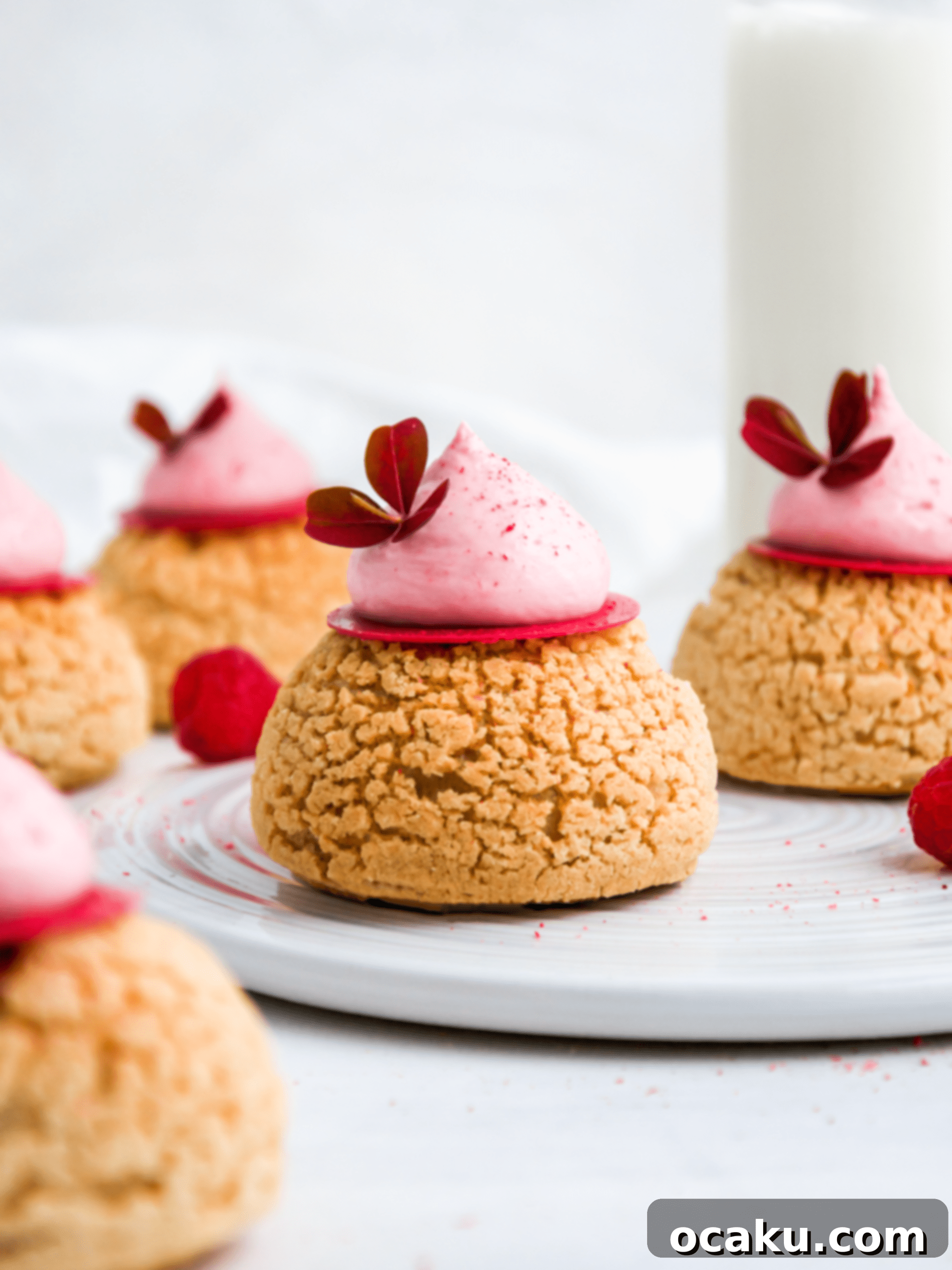 Several Raspberry Choux au Craquelin pastries arranged neatly on a serving plate.