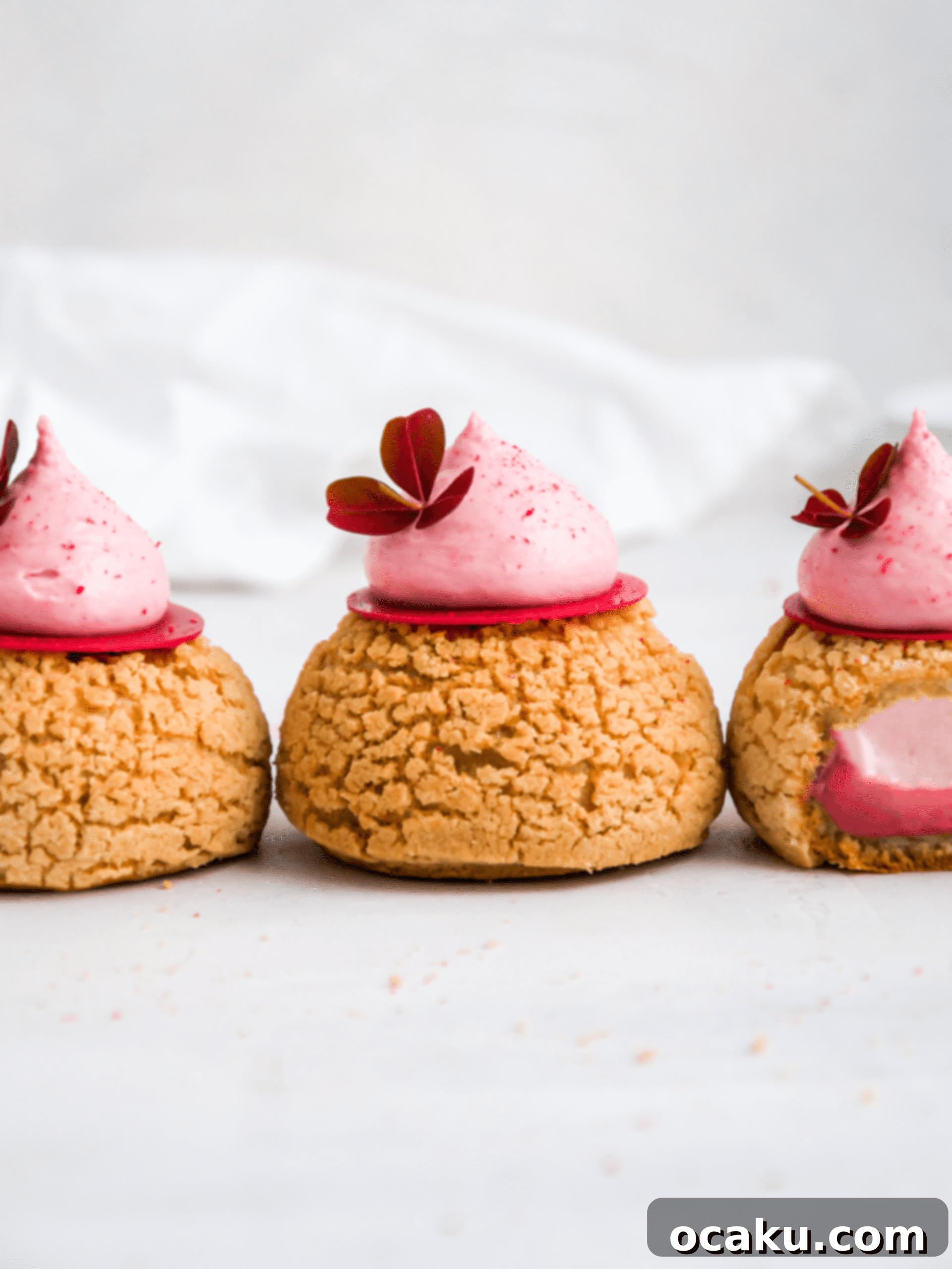 Close-up of a Raspberry Choux au Craquelin with a dollop of cream and raspberry garnish.