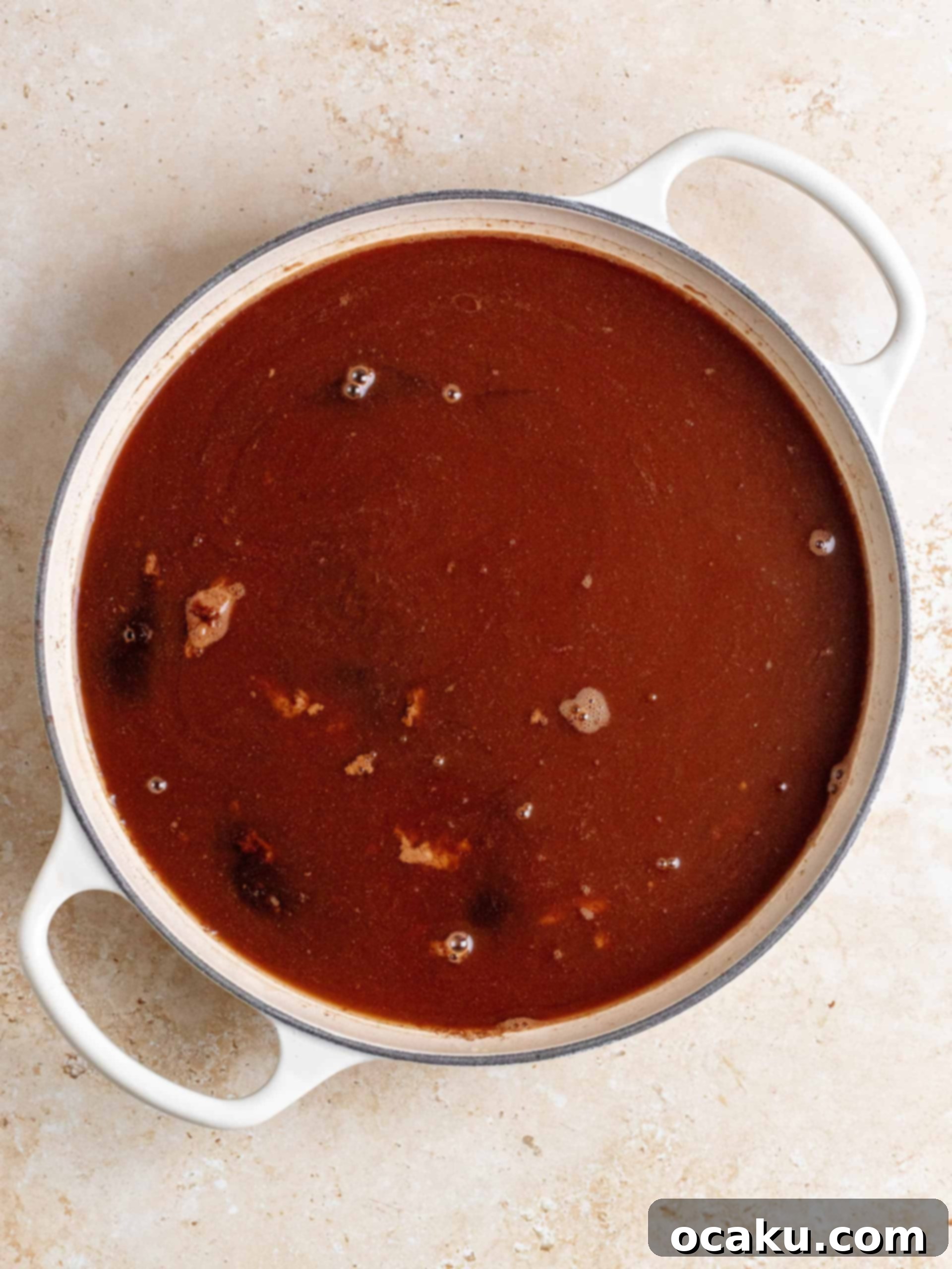 A serving of warm Brown Butter Hot Fudge Cake topped with a scoop of melting vanilla ice cream, ready to be enjoyed.