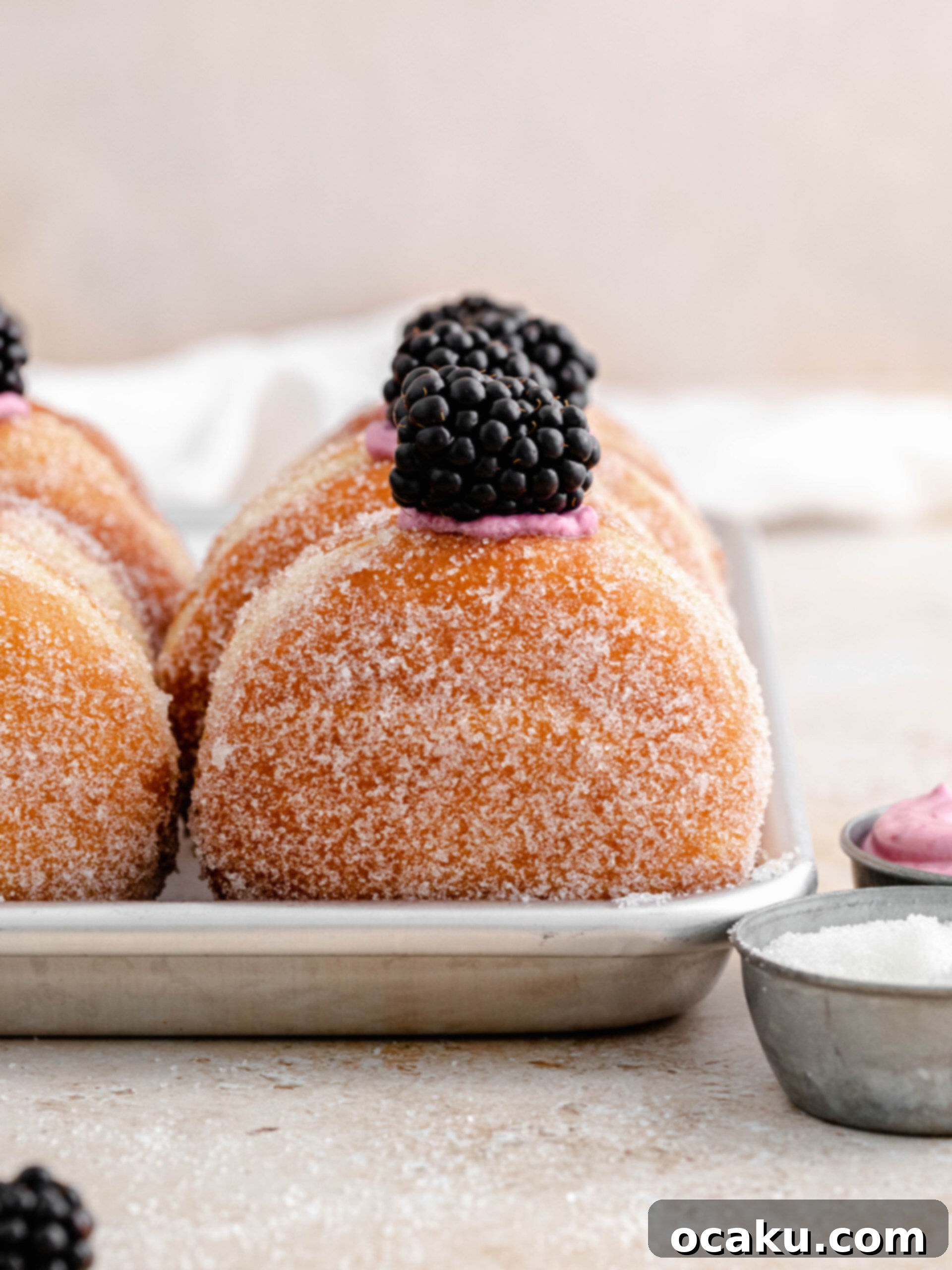 Cut donut rounds placed on parchment paper squares for second rise.