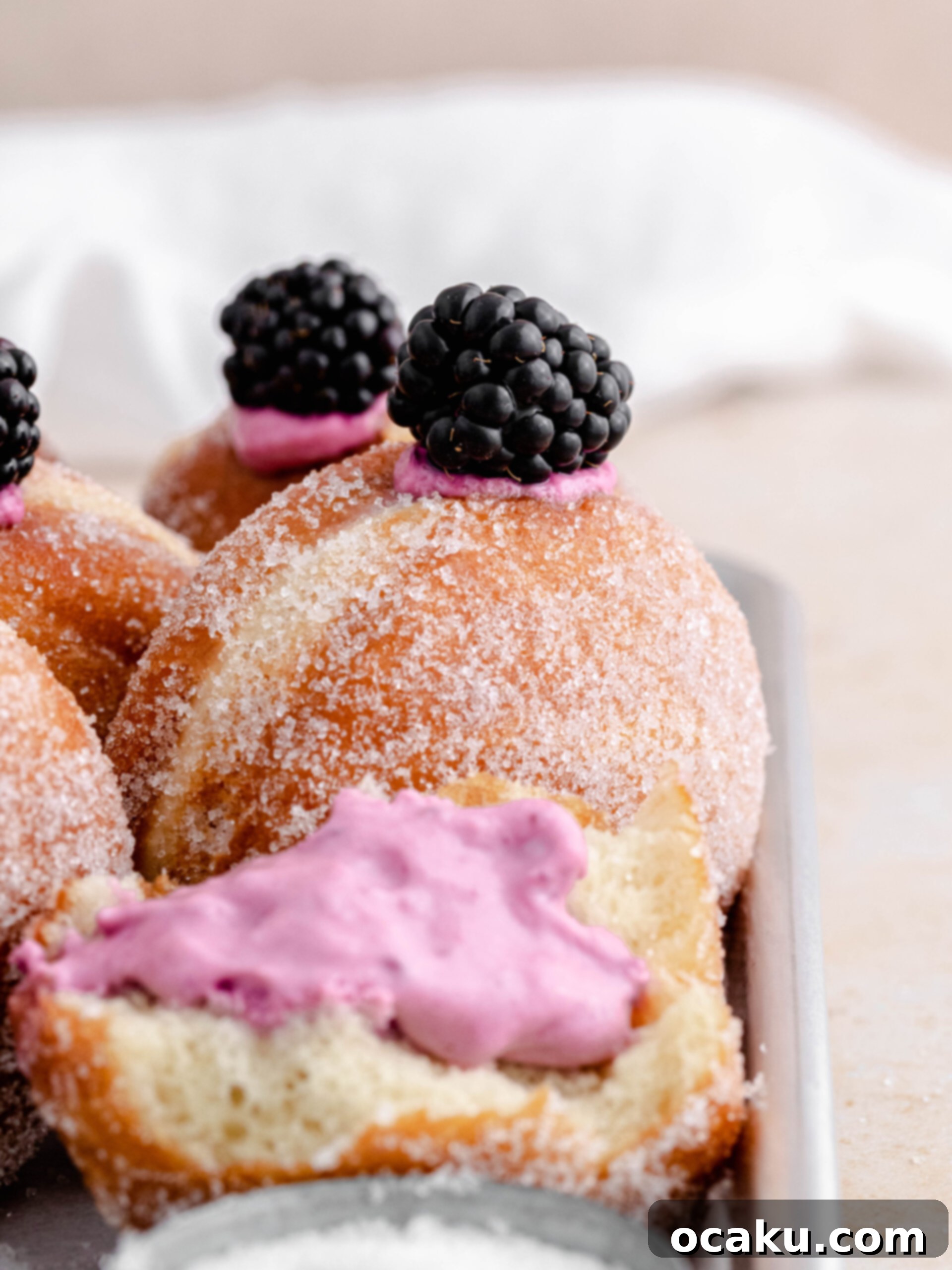 Close-up of a tray filled with freshly prepared blackberry cheesecake donuts.
