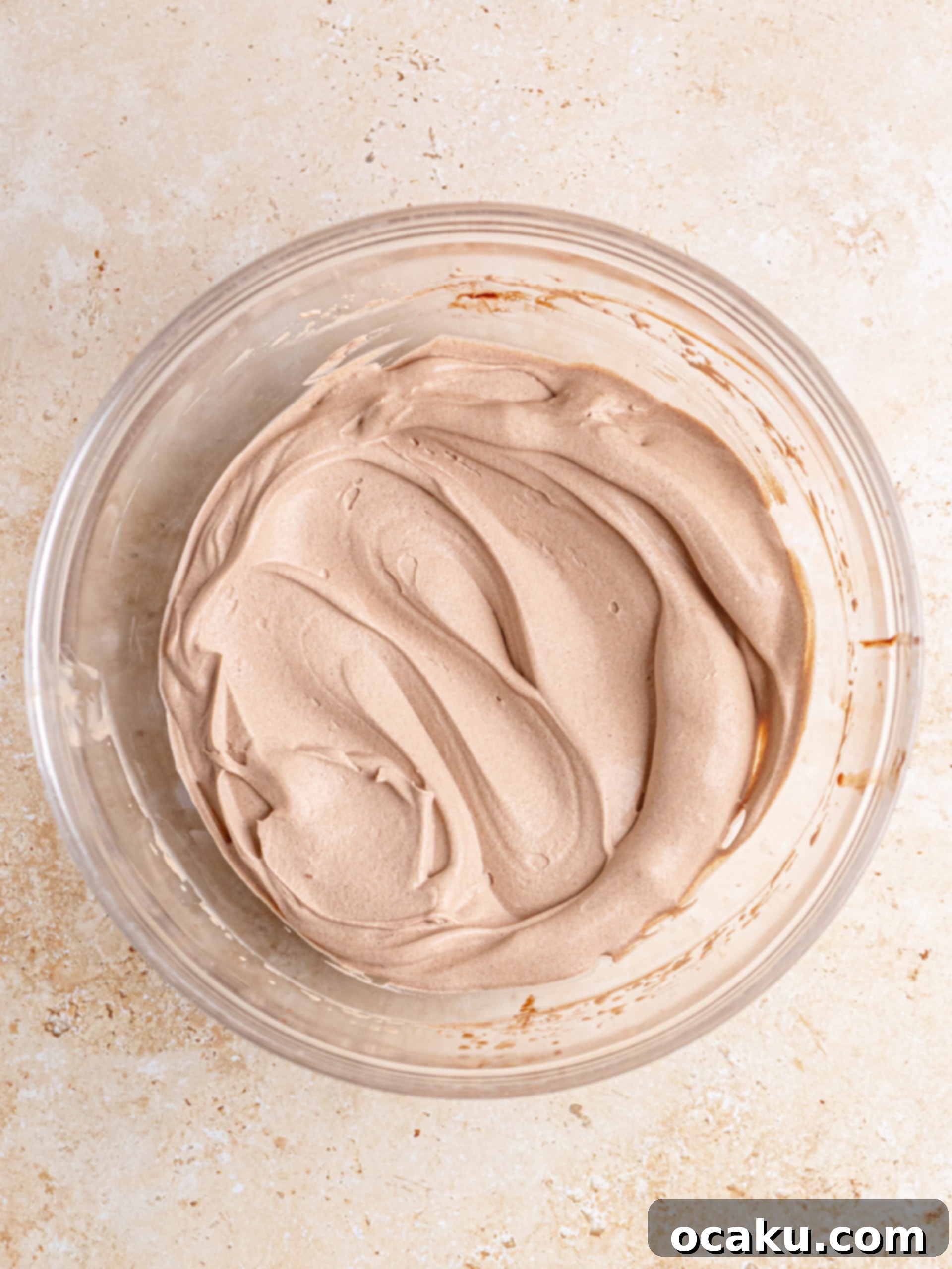 Decadent Chocolate Cheesecake 11 Luxurious whipped dark chocolate ganache being skillfully spread onto the top of a chocolate cheesecake.