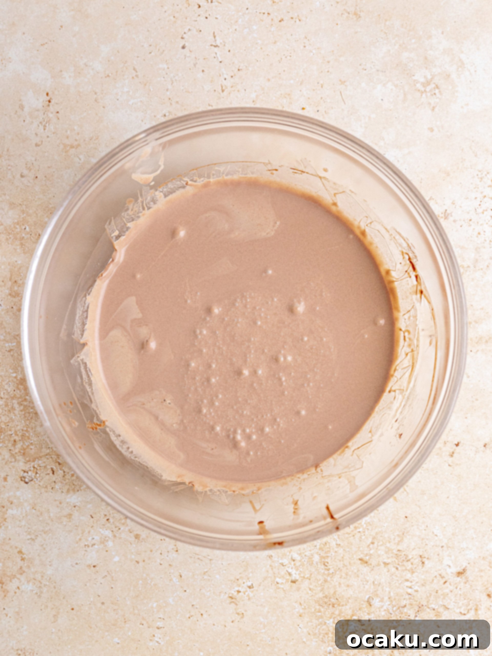 Decadent Chocolate Cheesecake 10 Melted dark chocolate and cream being combined in a bowl, showing the smooth texture of the ganache base.