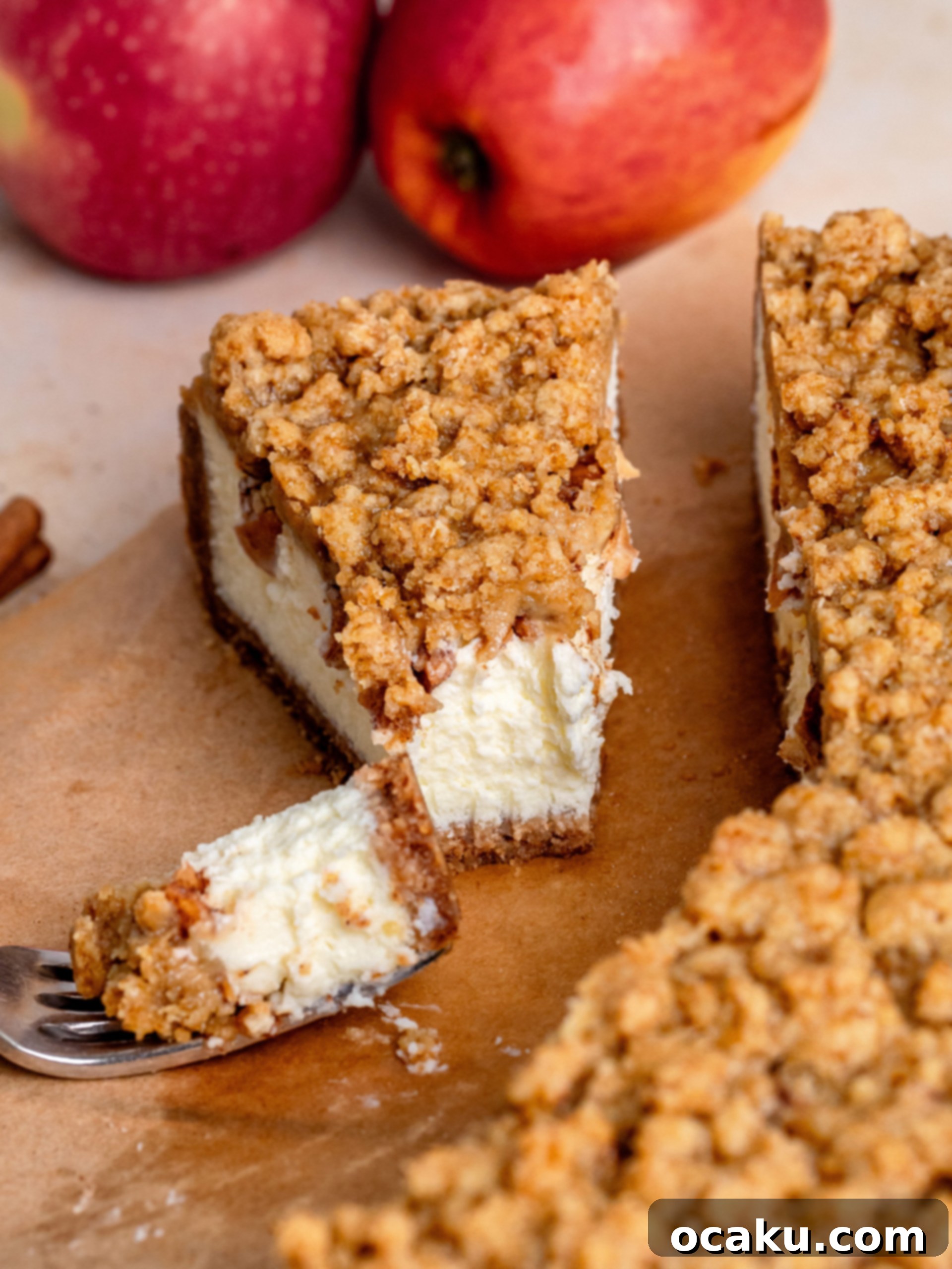 A close-up view of the rich, creamy Apple Crumble Cheesecake slice, showing the distinct layers of crust, filling, apples, and crumble.